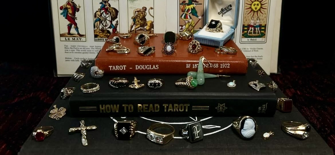 A collection of tarot cards, jewelry, and books on tarot reading displayed on a surface.