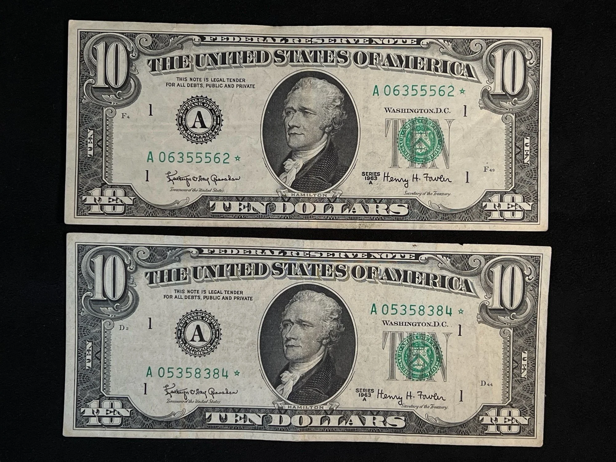 Two ten-dollar bills with portrait of Andrew Jackson, green Treasury seals, and serial numbers on a black surface.