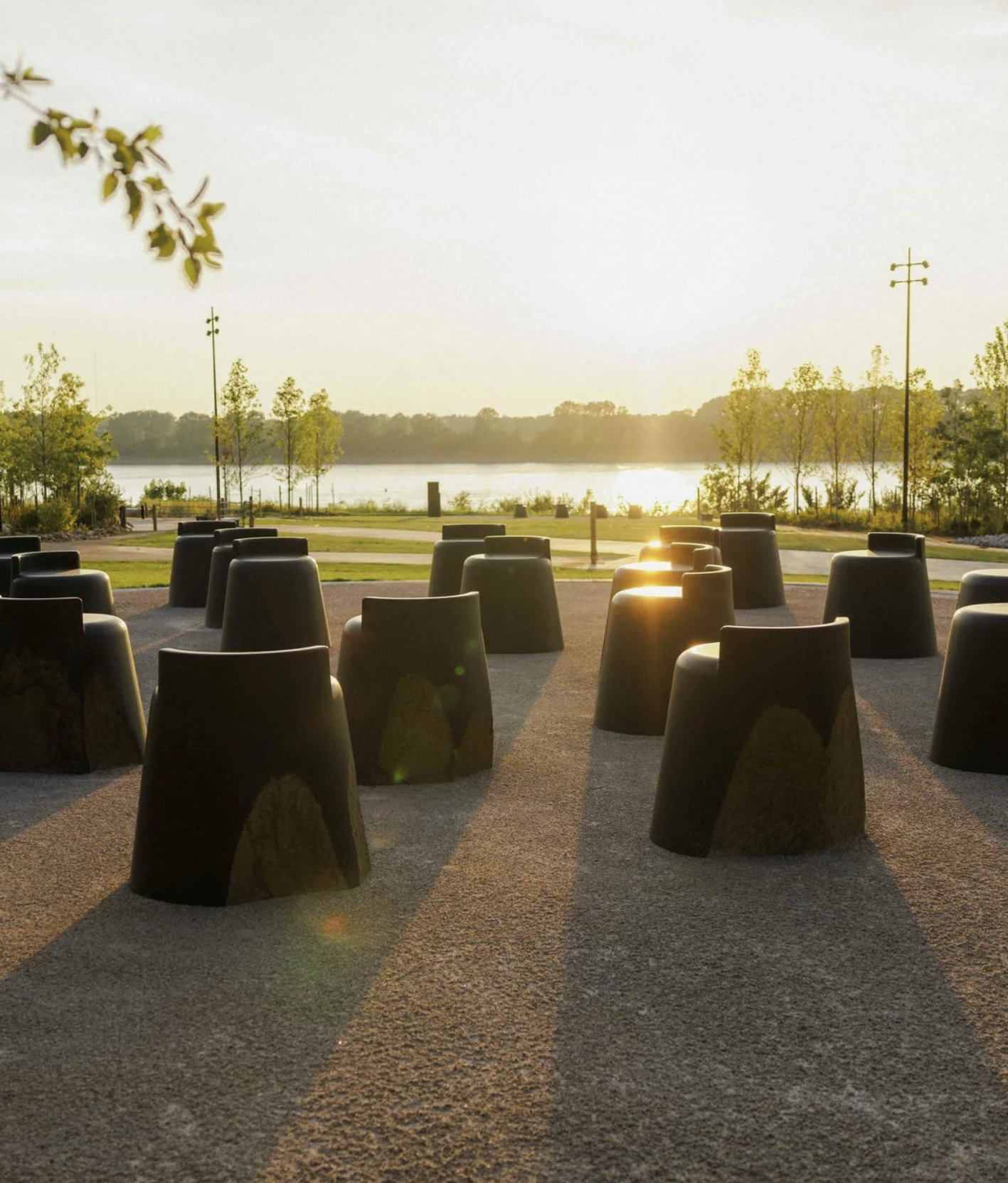 Outdoor seating area with black modern chairs, overlooking a body of water and trees at sunset.