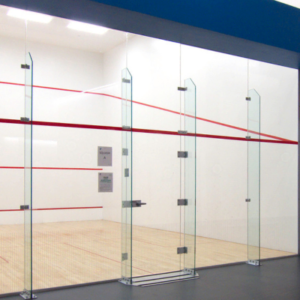 Showcasing a project by DOUBLEPLAY: Empty racquetball court with glass walls, red lines, and a wooden floor.