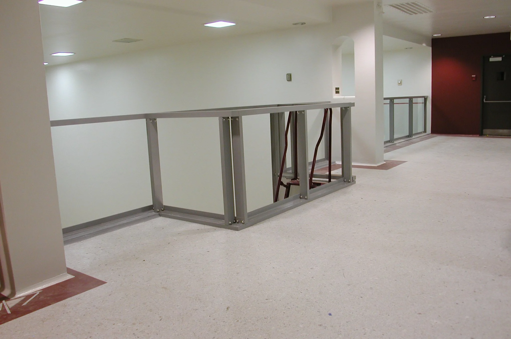 Showcasing a project by DOUBLEPLAY: Empty indoor hallway with white walls, a black door, and an empty metal railing or frame in the foreground.