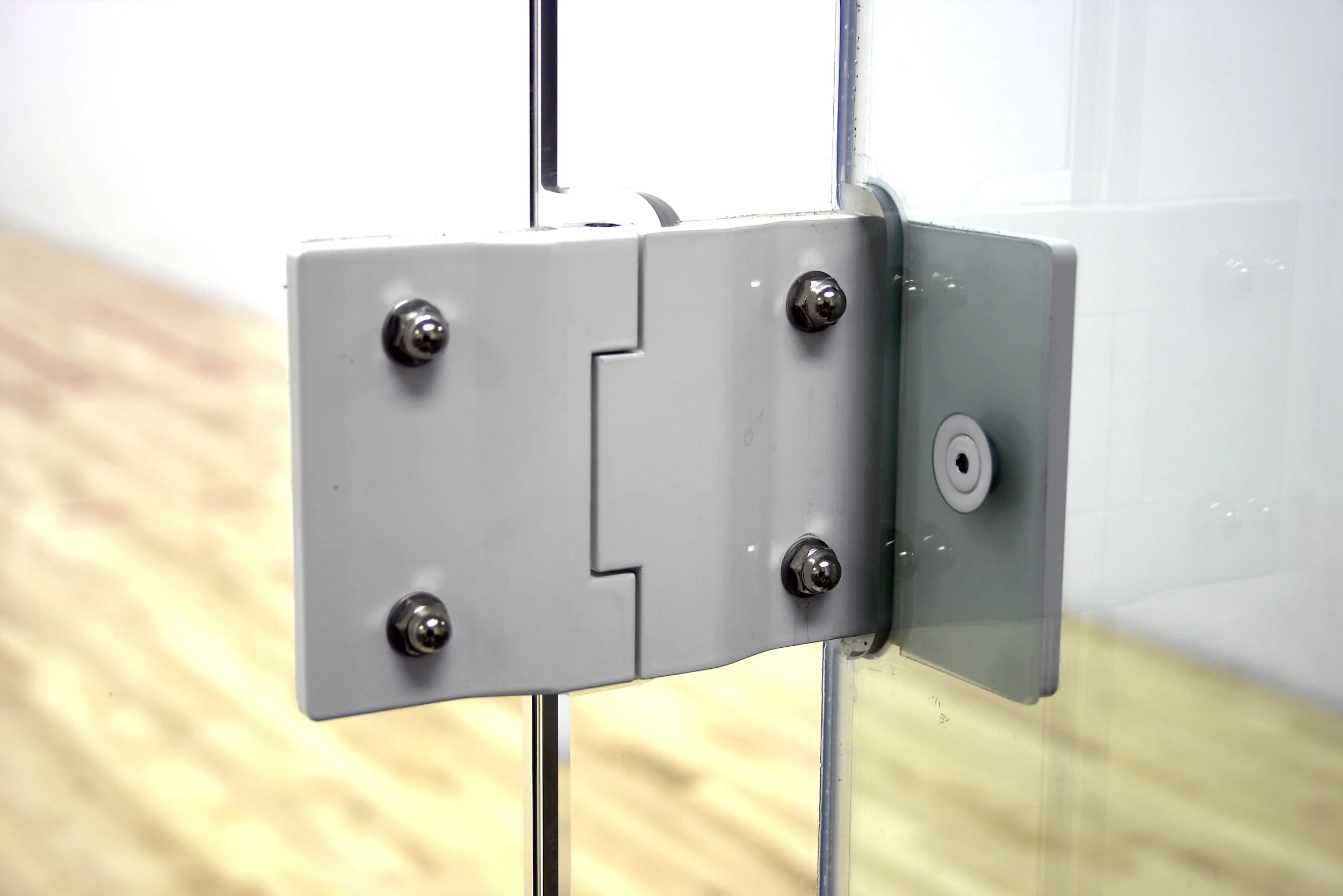 Design feature by DOUBLEPLAY: Close-up of a metallic hinge or mechanical part with screws, mounted on a surface, with bolts and a black cable attached.