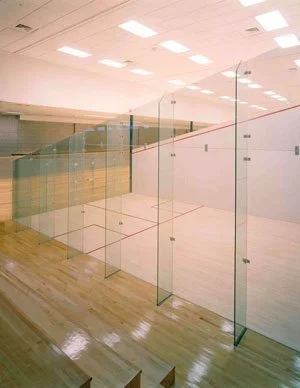 Showcasing a project by DOUBLEPLAY: Empty indoor sports court with glass walls and wooden flooring.