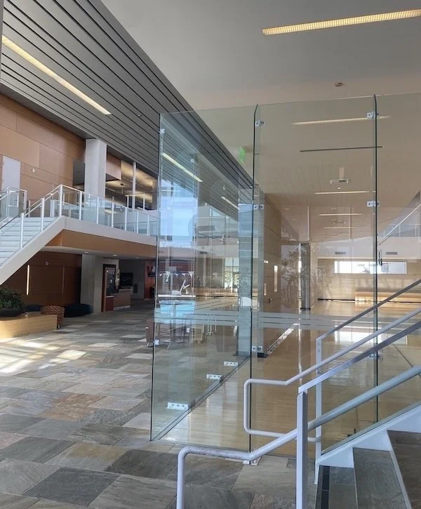 Showcasing a project by DOUBLEPLAY: Interior of a modern building with glass walls, stairs, and an open floor plan.