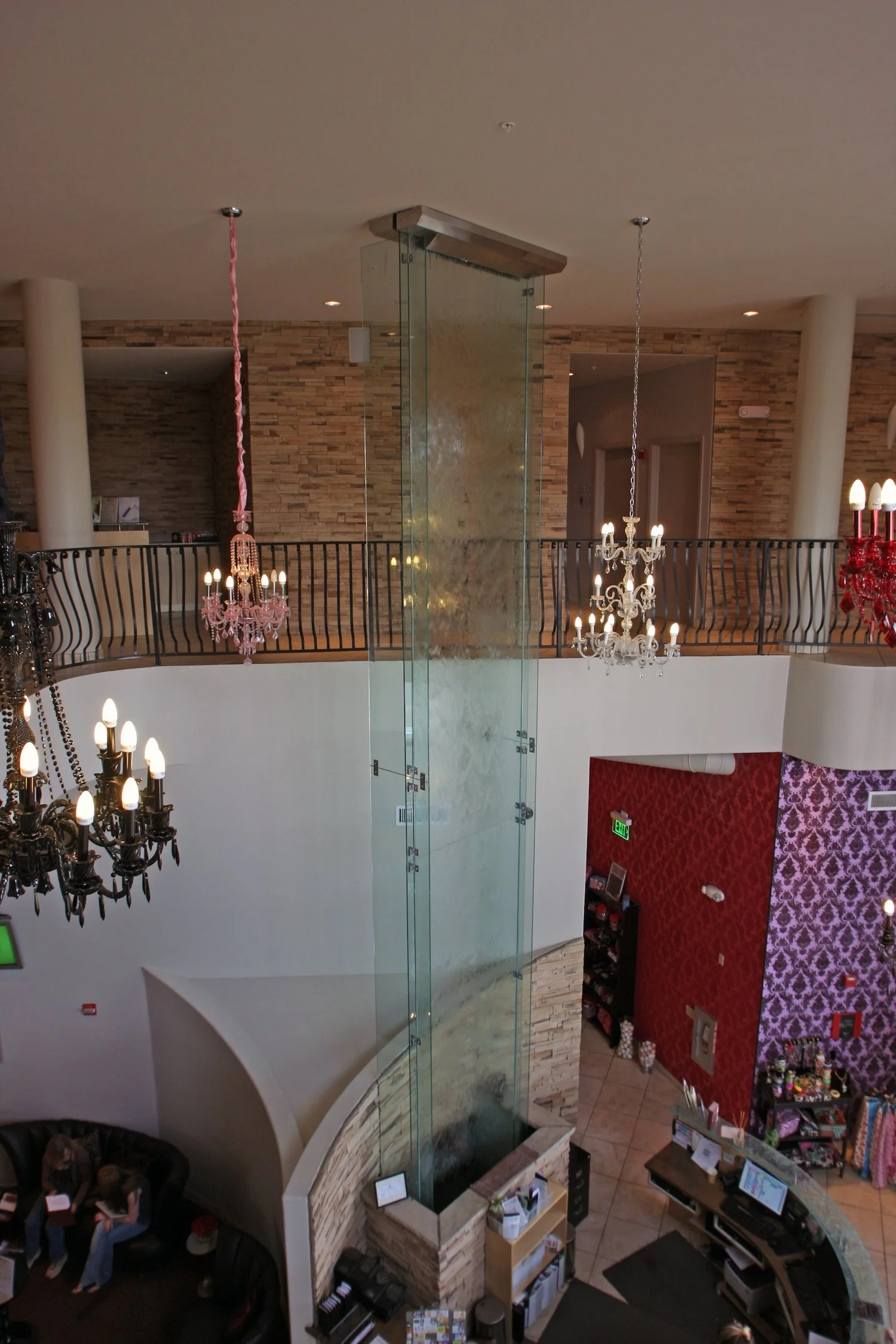 Showcasing a project by DOUBLEPLAY: Interior view of a multi-level building with chandeliers, a brick wall, and reception or retail area.