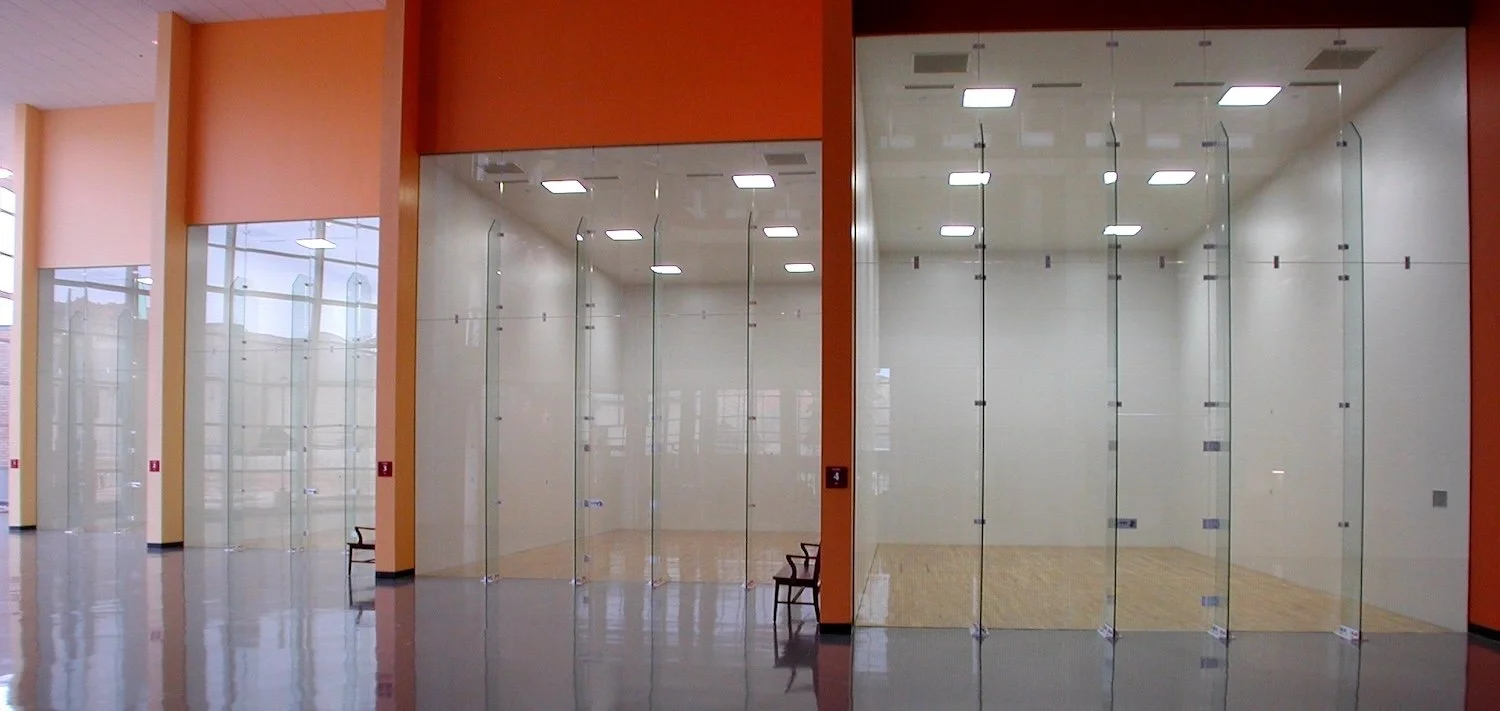 Showcasing a project by DOUBLEPLAY: Empty glass-walled rooms in a modern building, with few chairs and reflective floors.
