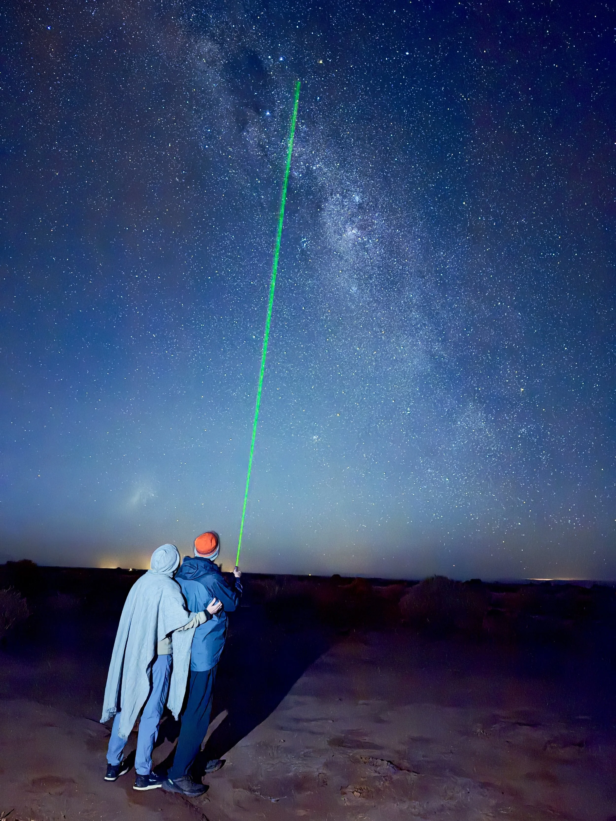 Astronomy guide pointing a green laser pointer at the Milky Way and southern constellations during a stargazing tour in San Pedro de Atacama.