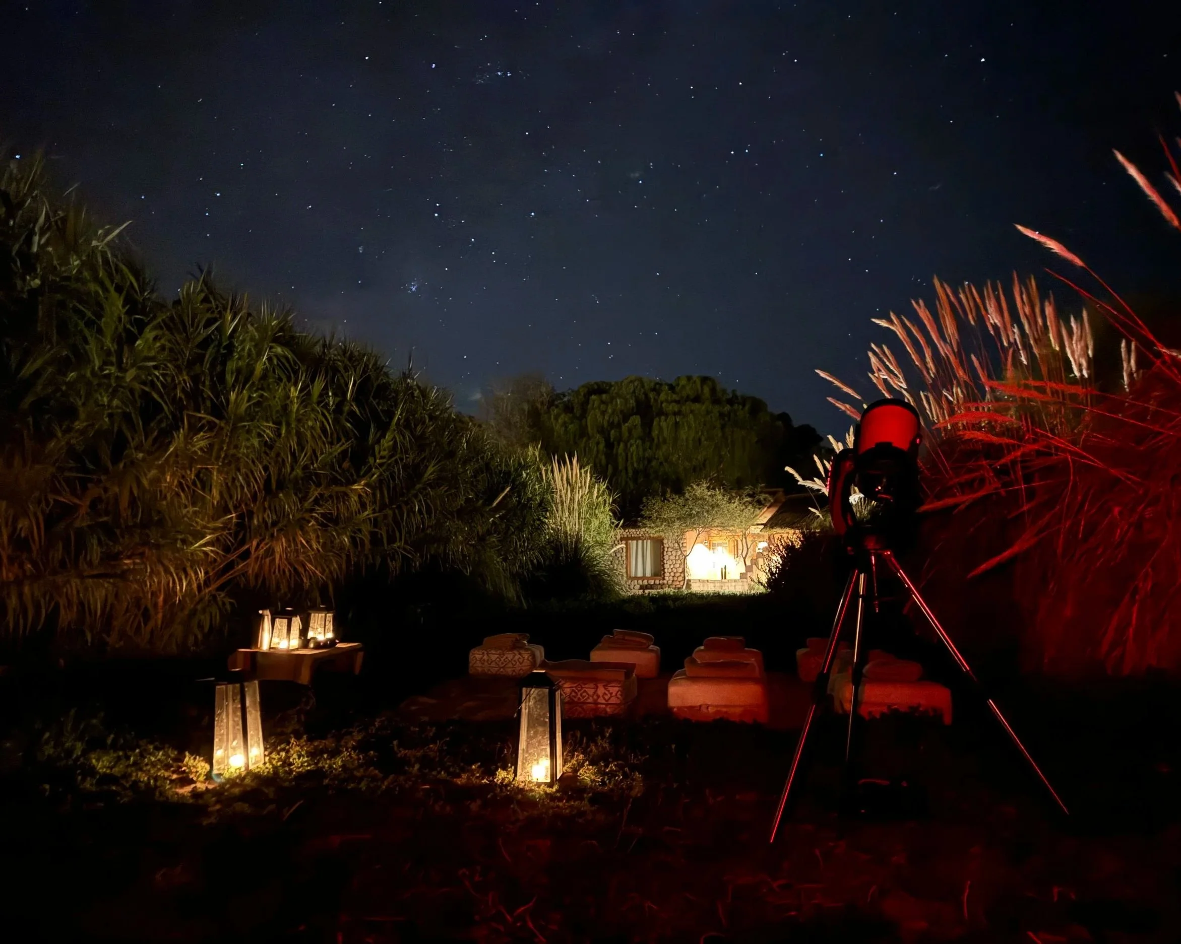 Mobile observatory stargazing setup featuring floor cushions, lanterns, and a telescope under a starry night sky in San Pedro de Atacama.