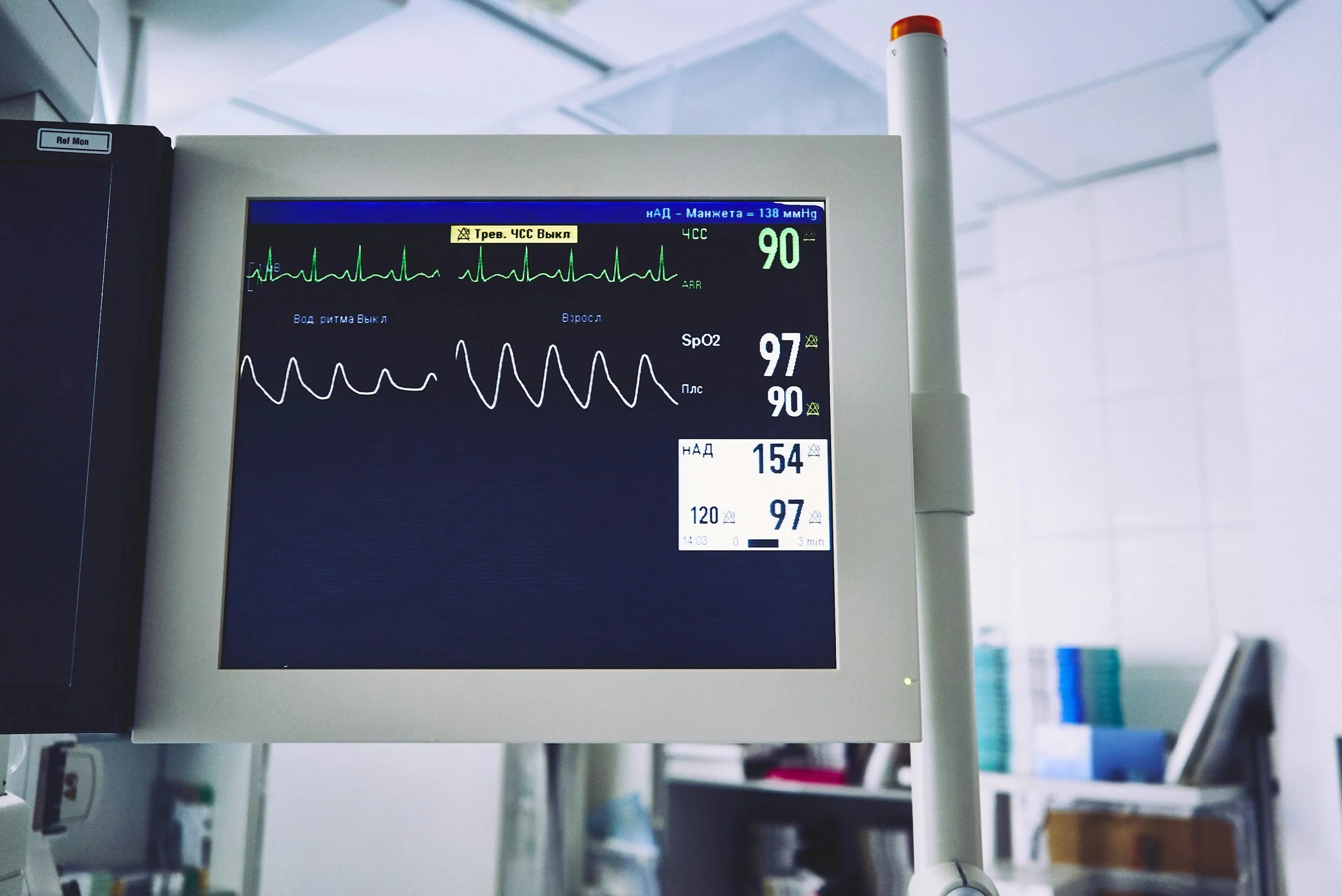 Medical monitor displaying heart rate, oxygen saturation at 97%, blood pressure, and other vital signs in a clinical setting.