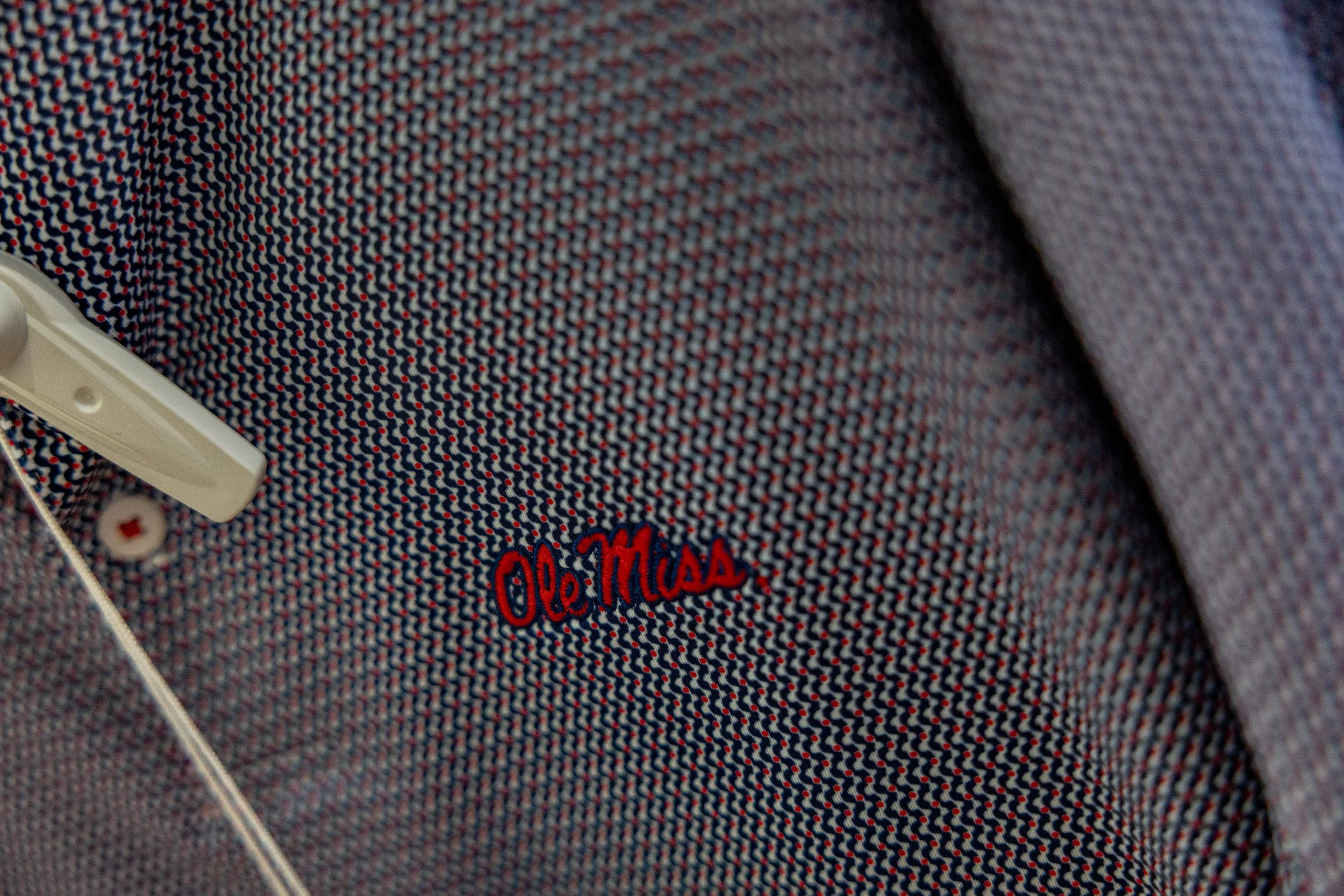 Close-up of a fabric with red, white, and blue thread pattern with embroidered red text 'Ole Miss'.