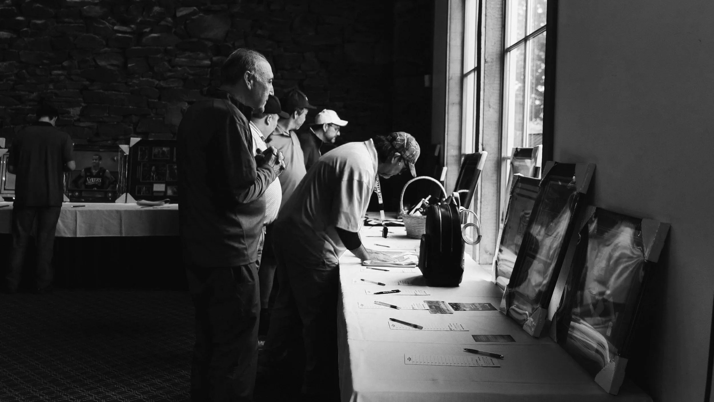 People at a table looking at framed pictures or artwork in a gallery or exhibit space.