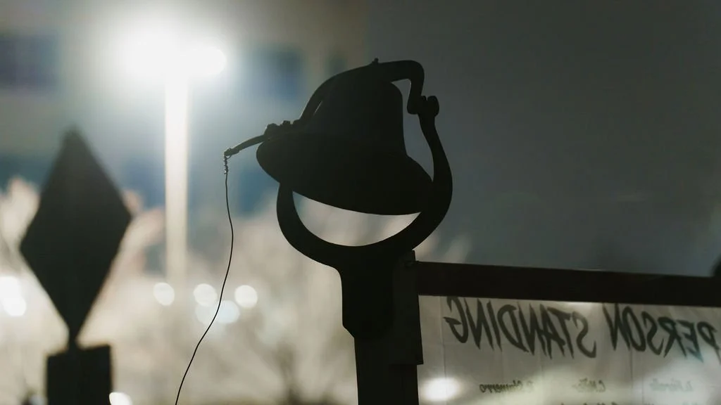 Silhouette of a vintage desk lamp against a bright background, with a blurred outdoor scene visible.