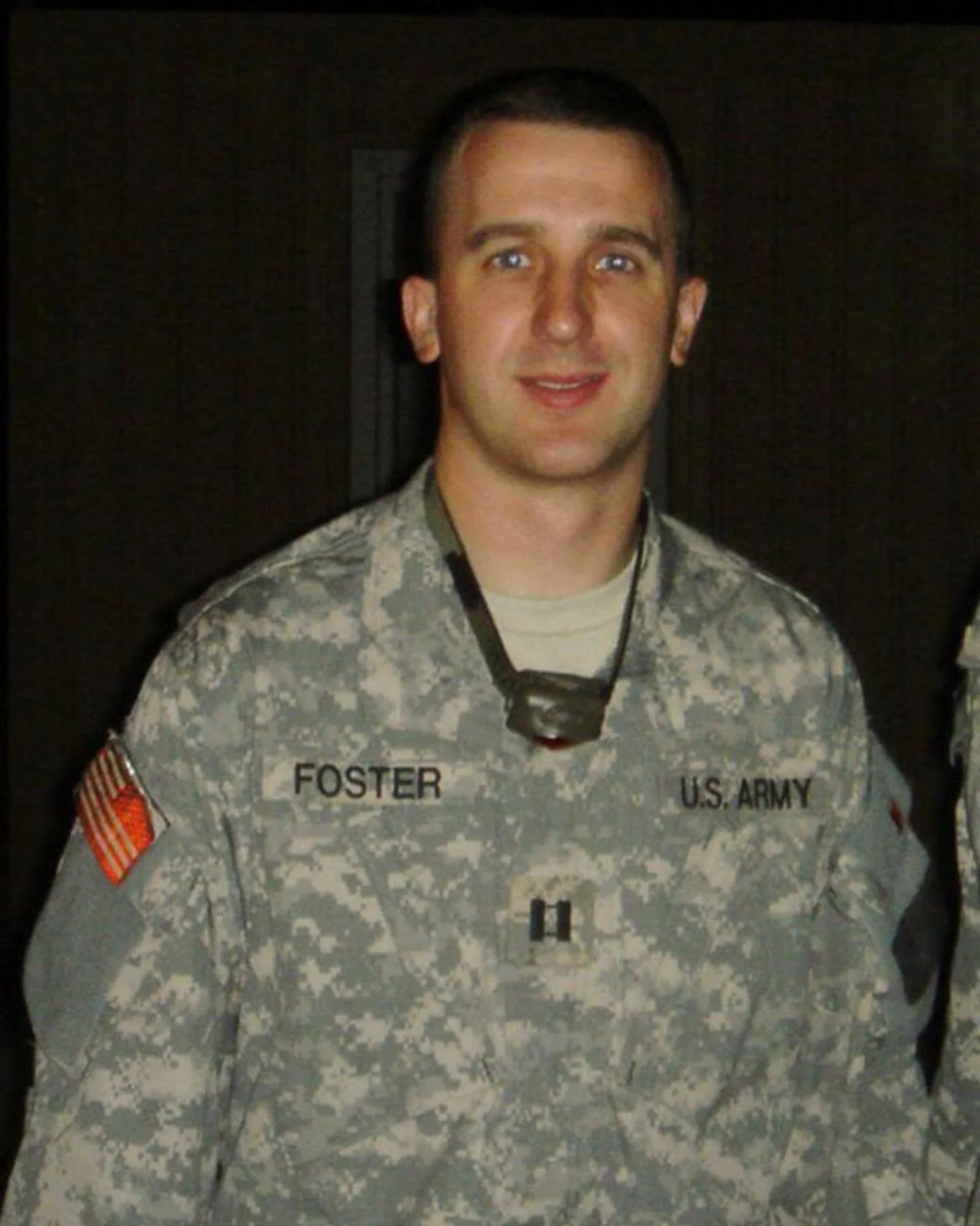 Man in U.S. Army camouflage uniform with name tag 'Foster', wearing a headlamp, standing in a dark area.