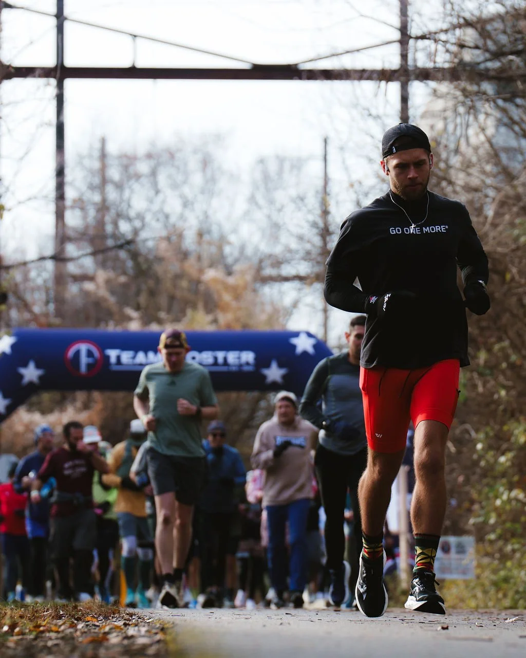 People running in a race near a starting line that says 'TEAM NOVESTER' under an arch.