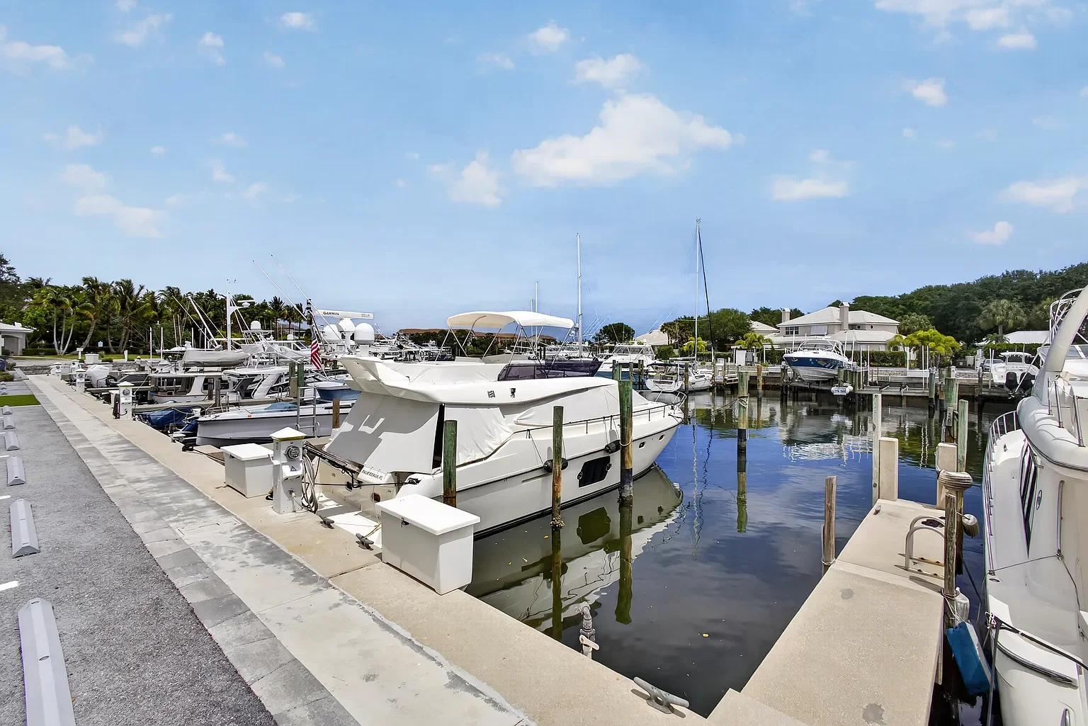 Marina filled with boats and yachts docked along the pier on a clear, sunny day.