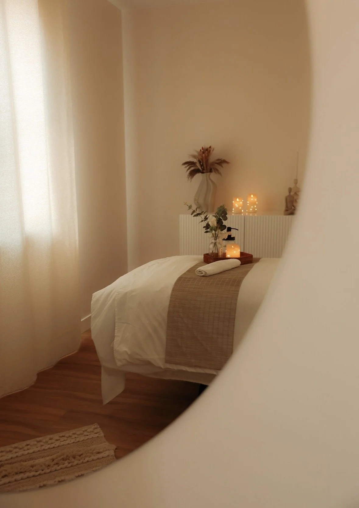 Une chambre calme avec un lit, décorée de bougies et de plantes, ambiance chaleureuse et apaisante.