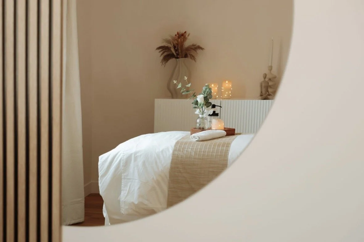 Vue d'un lit dans une chambre décorée avec des bougies, un vase avec des fleurs, une figure en cire et un miroir rond