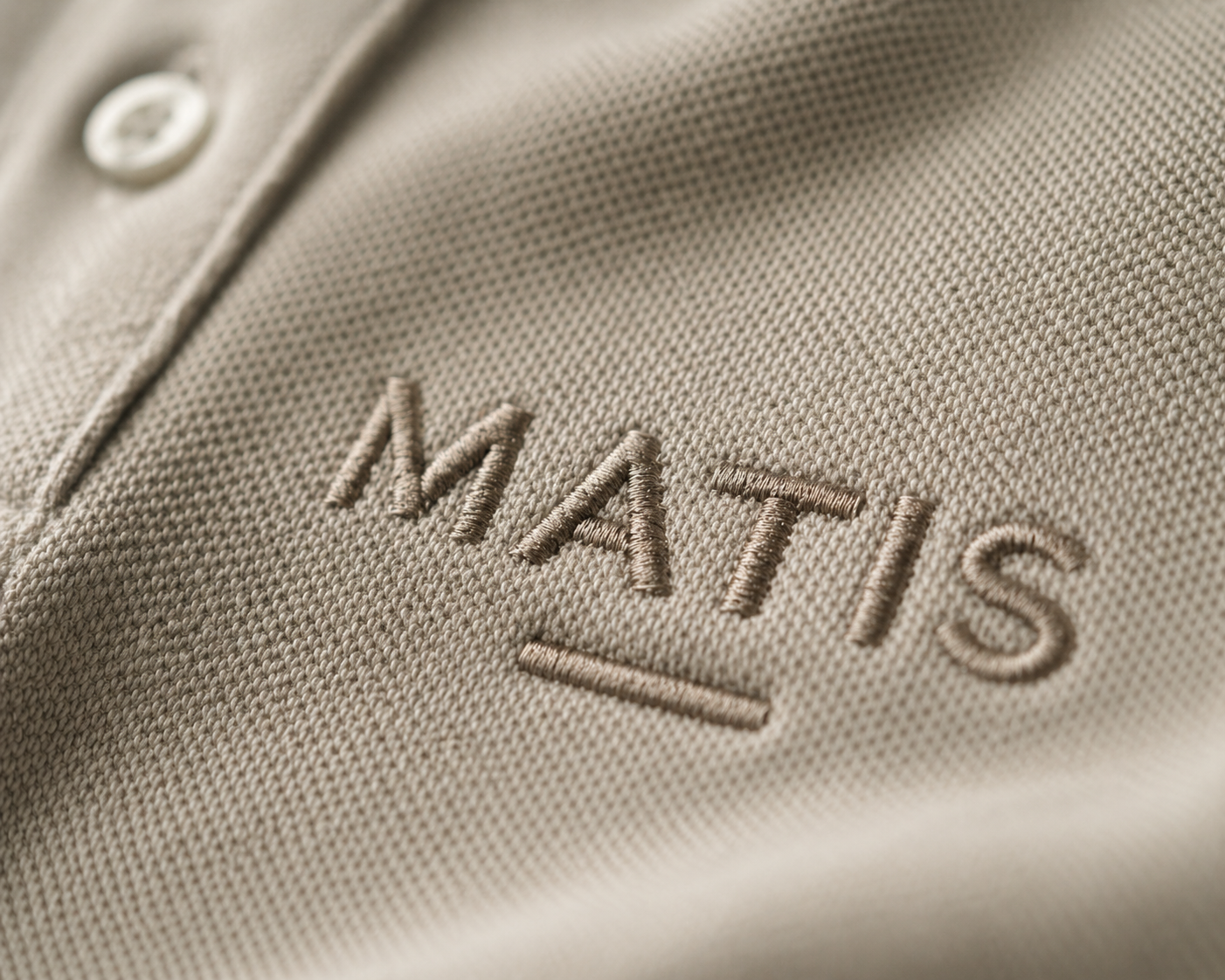 Nahaufnahme eines grauen Stoffteils mit aufgesticktem Logo "MATTIS".