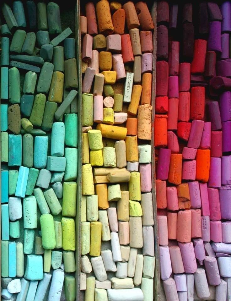 A colorful display of chalks arranged by color, including shades of green, yellow, orange, pink, and purple.