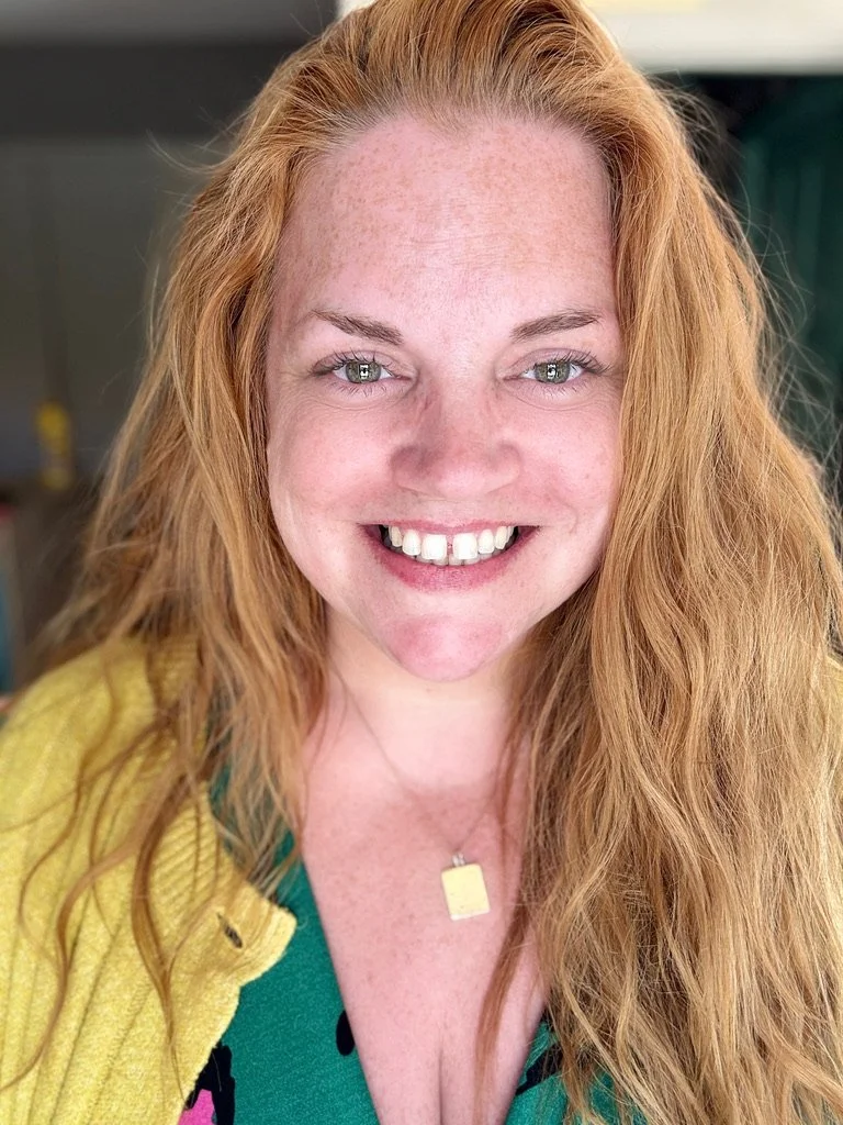 Close-up of Jodie smiling, in a yellow cardigan