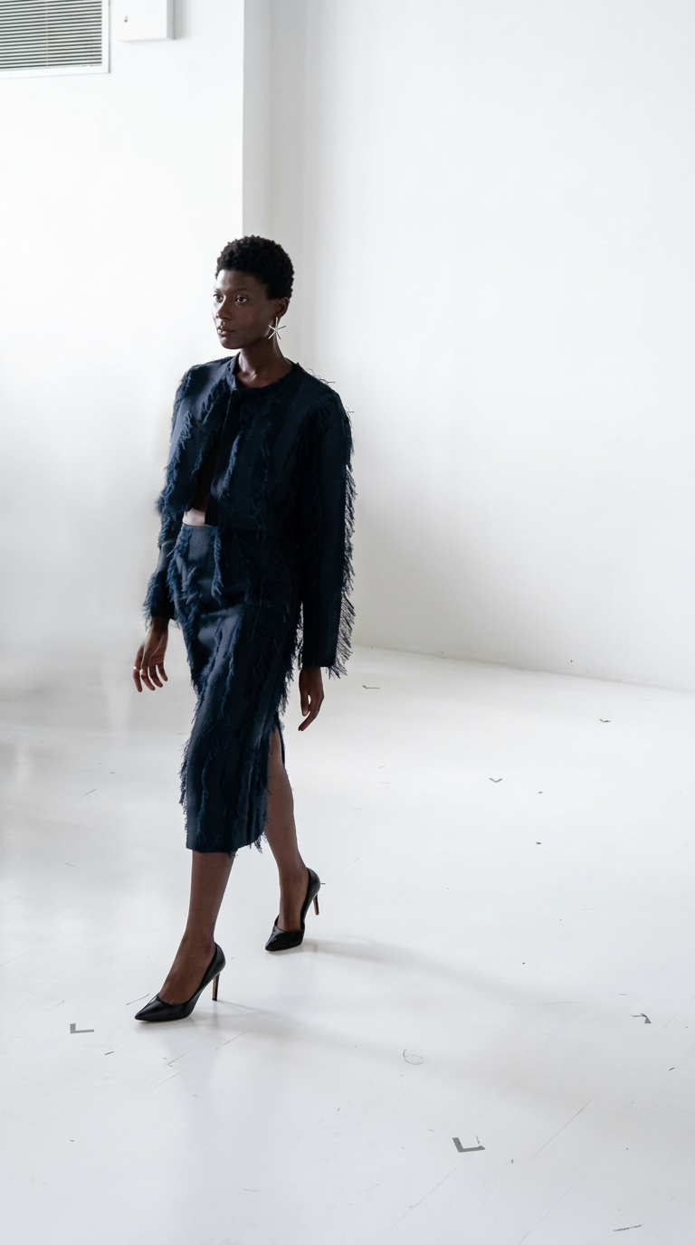 Part discipline, part disruption. A sharply cut navy ensemble comes alive through tactile fringe detailing, turning a classic silhouette into a study of movement, mood, and modern femininity