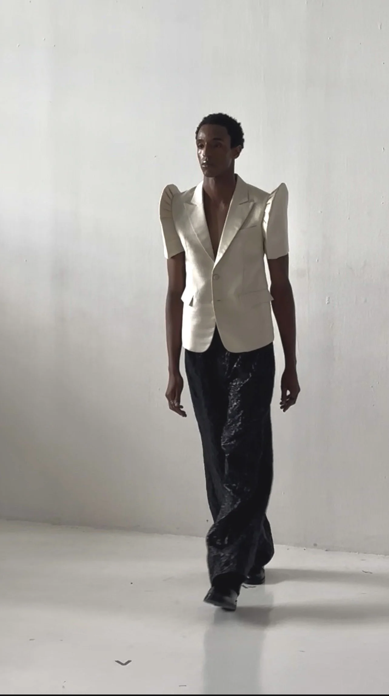 A sharply tailored ivory blazer with sculptural shoulders is paired with fluid black textured trousers, creating a striking balance between architectural precision and effortless movement. The look exemplifies Floresca’s modern approach to power dres