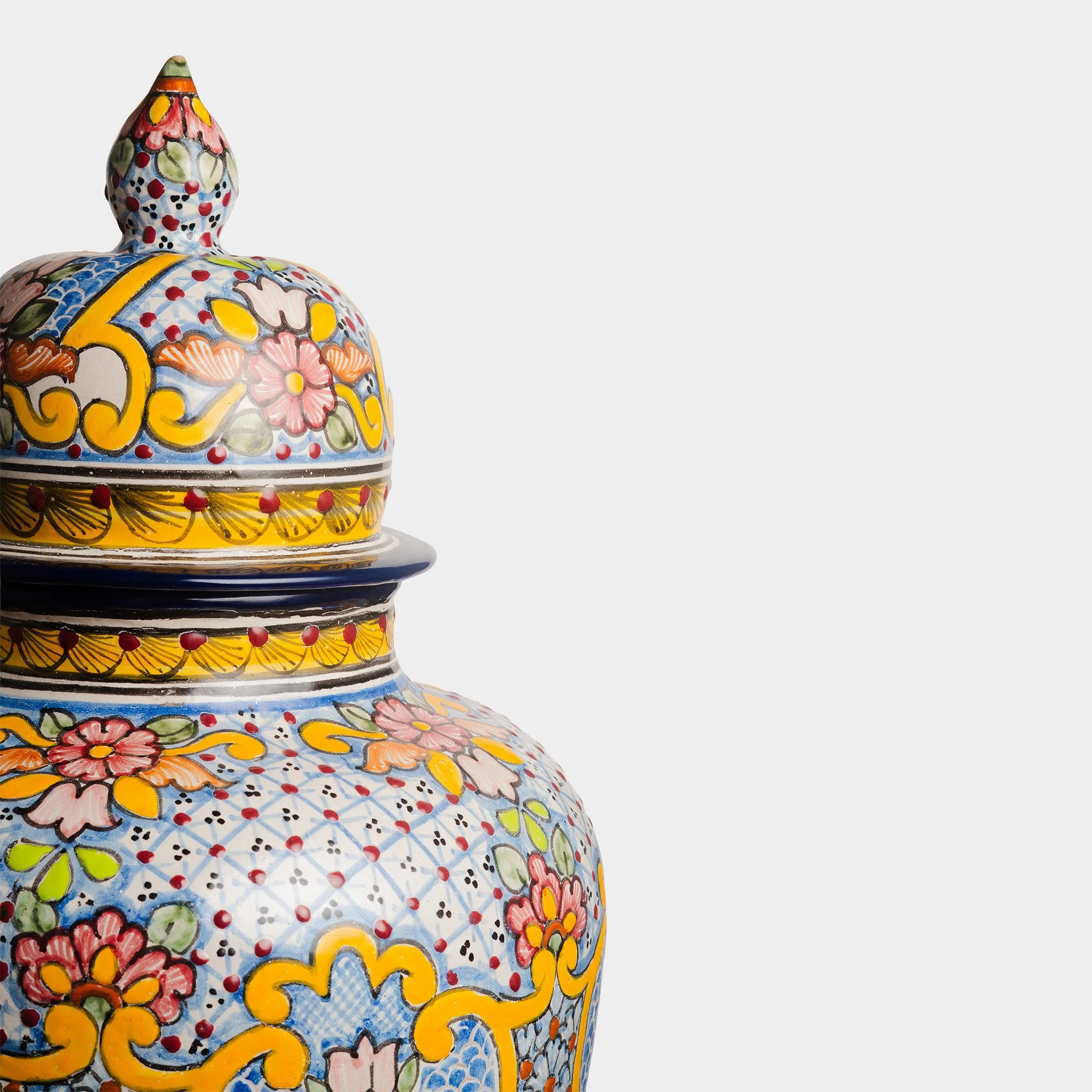 Tibor de talavera decorado con flores, hojas y patrones en colores vivos, en tonos azules, amarillos, rojos, verdes y rosa.
