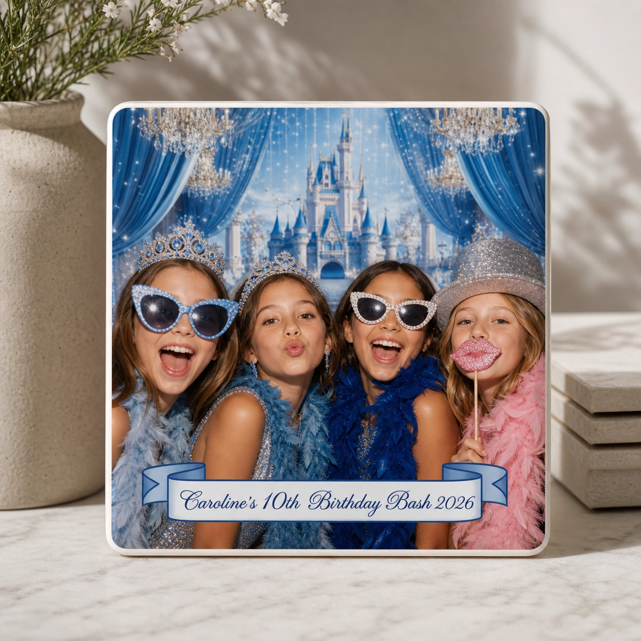 Photo of four girls dressed in blue and pink feather boas, wearing tiaras and fun glasses, posing with a Cinderella castle background. The image has a banner that reads 'Caroline's 10th Birthday Bash 2026'.