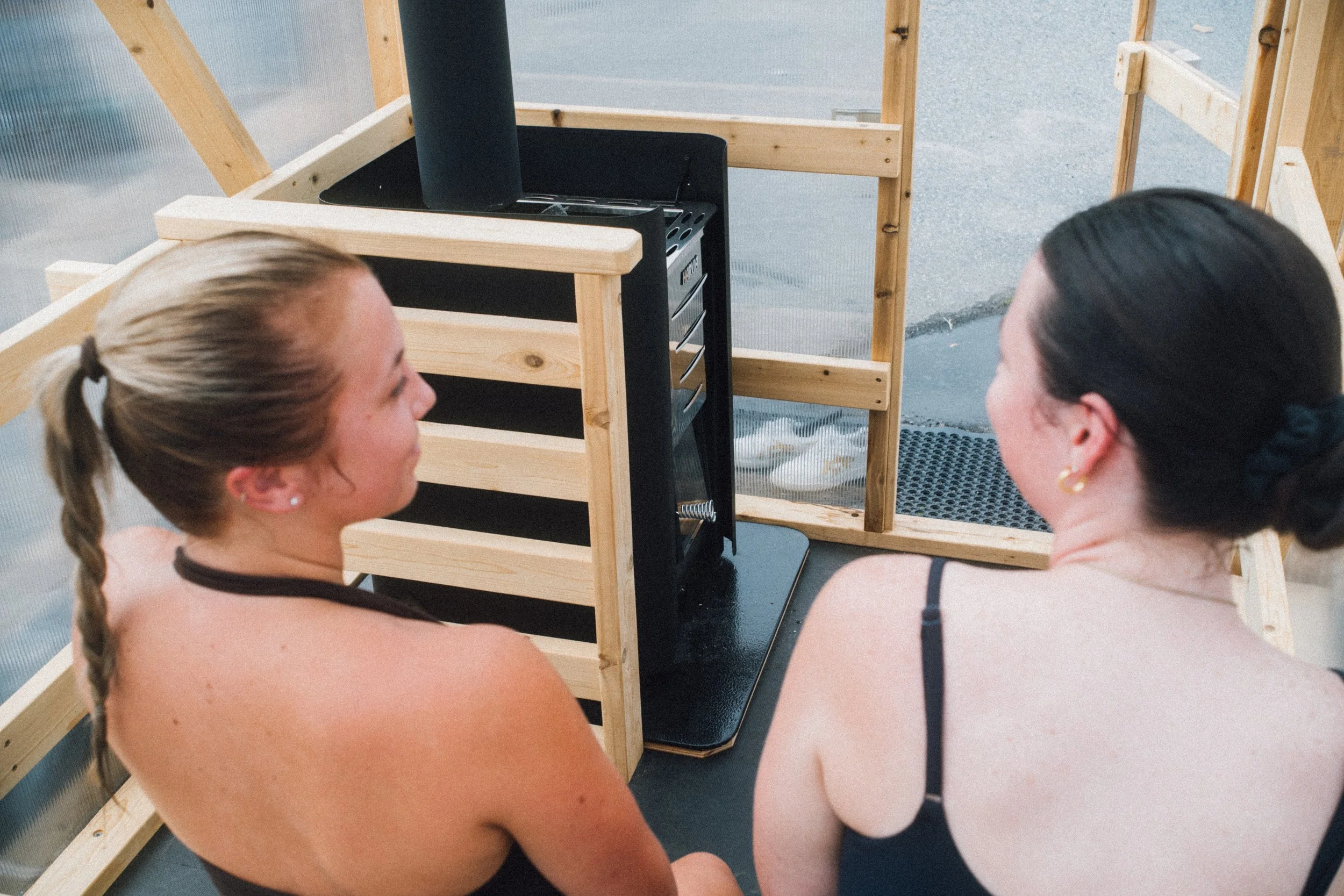 Image of two people sitting on a sauna bench with clear walls.