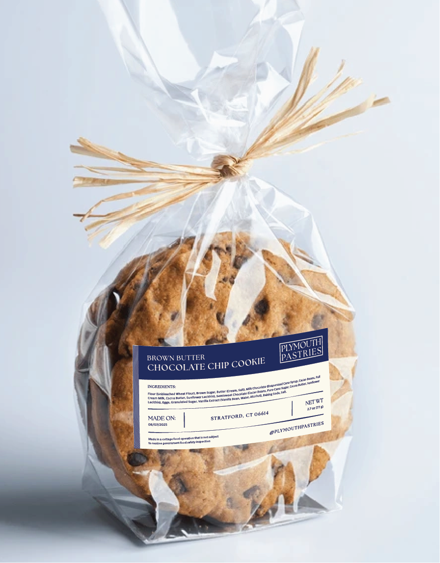 A clear plastic bag tied with raffia containing chocolate chip cookies labeled 'Brown Butter Chocolate Chip Cookie' from Plymouth Pastries.