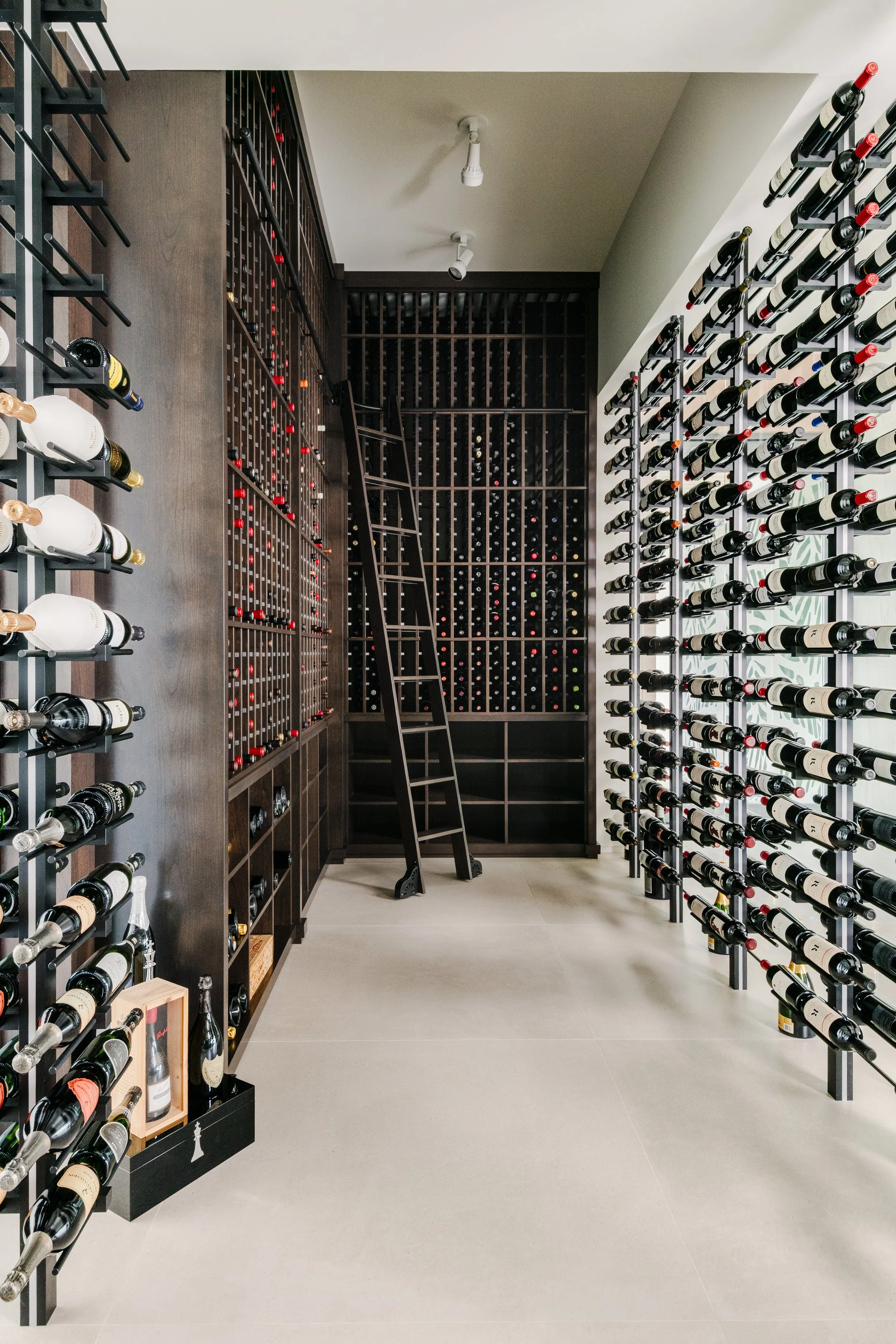 A wine cellar with dark wooden shelves and racks filled with various wine bottles in a modern setting.