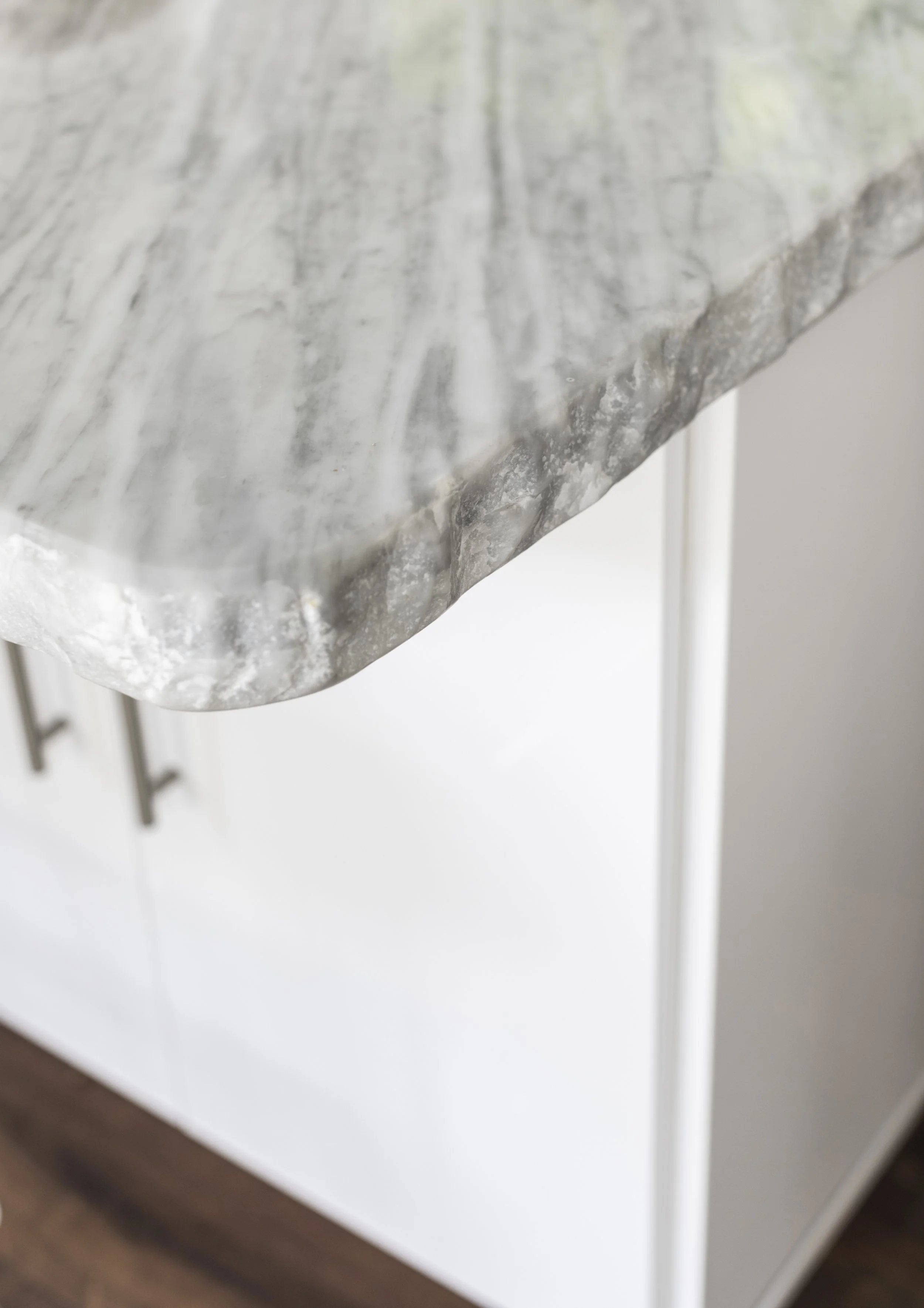 Close-up of a marble countertop with a gray and white pattern, mounted on a white cabinet with gray legs.
