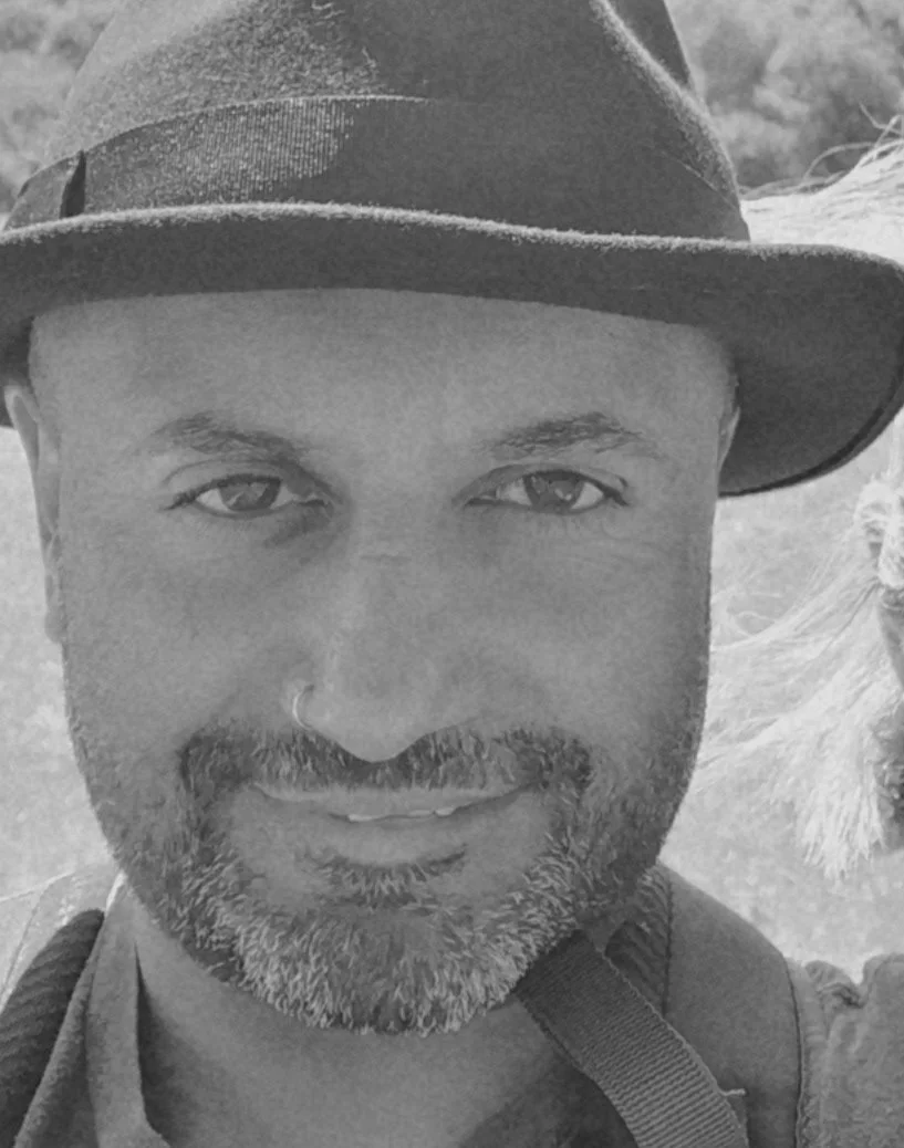 A portrait of the photographer wearing a wide-brimmed hat, with light facial hair, looking at the camera with a slight smile, outdoors.