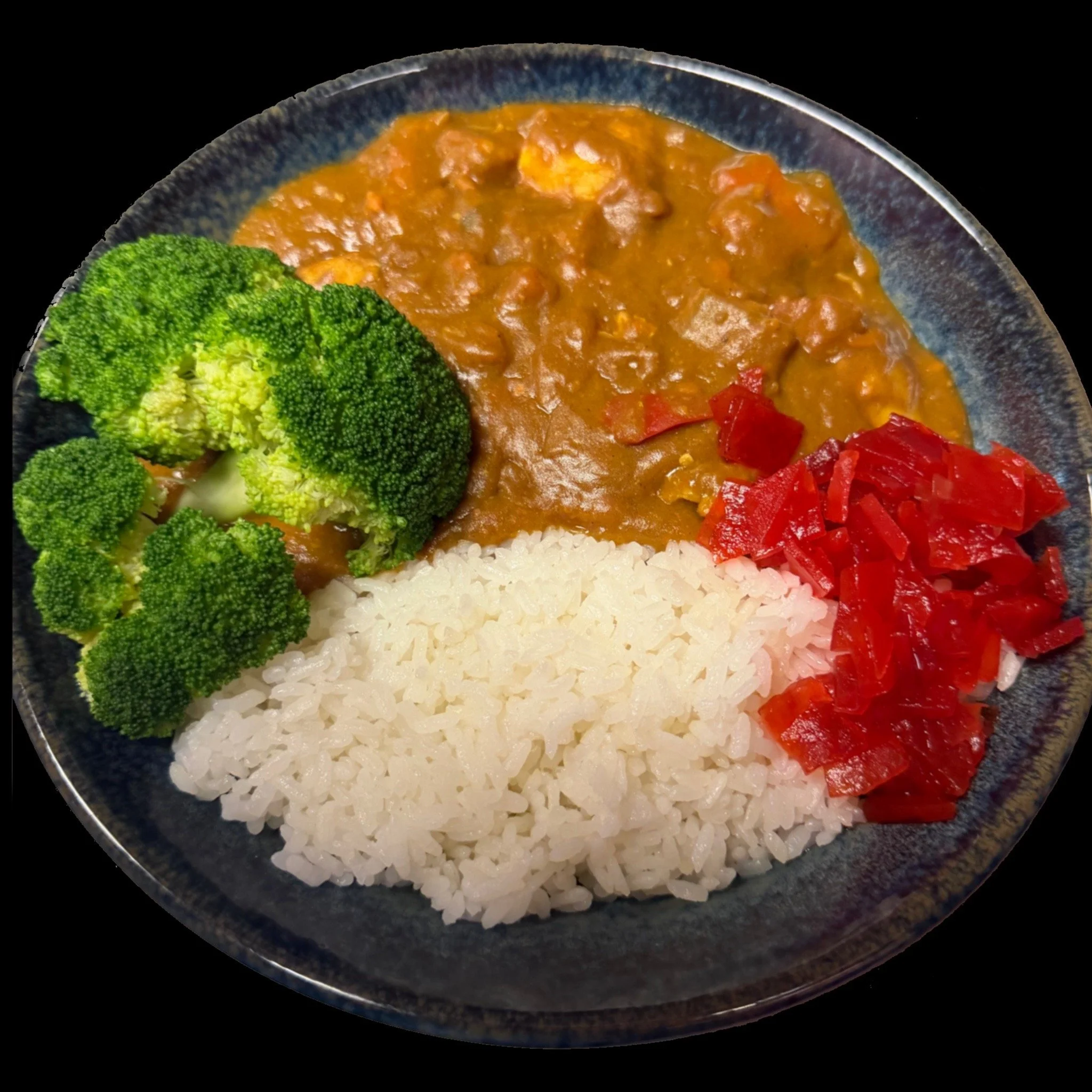 Close-up of a bowl filled with rice, broccoli, curry with vegetables, and chopped red peppers.