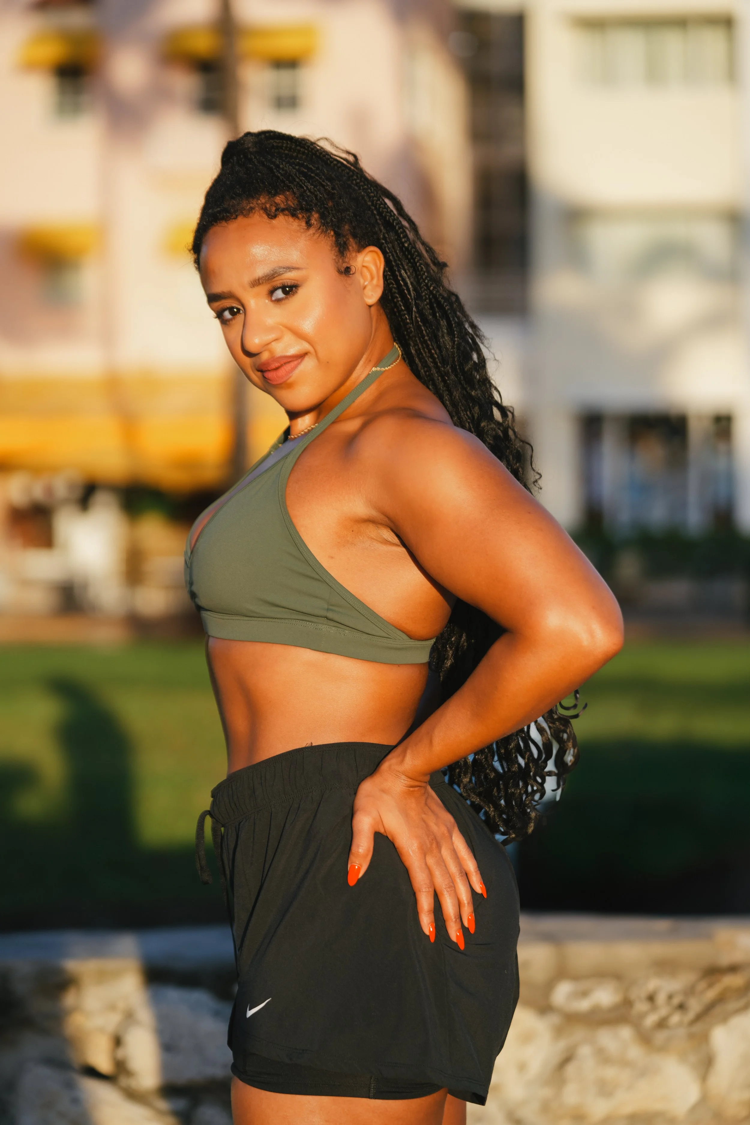 A woman in athletic clothing standing outdoors near water with rocks, smiling and looking at the camera.