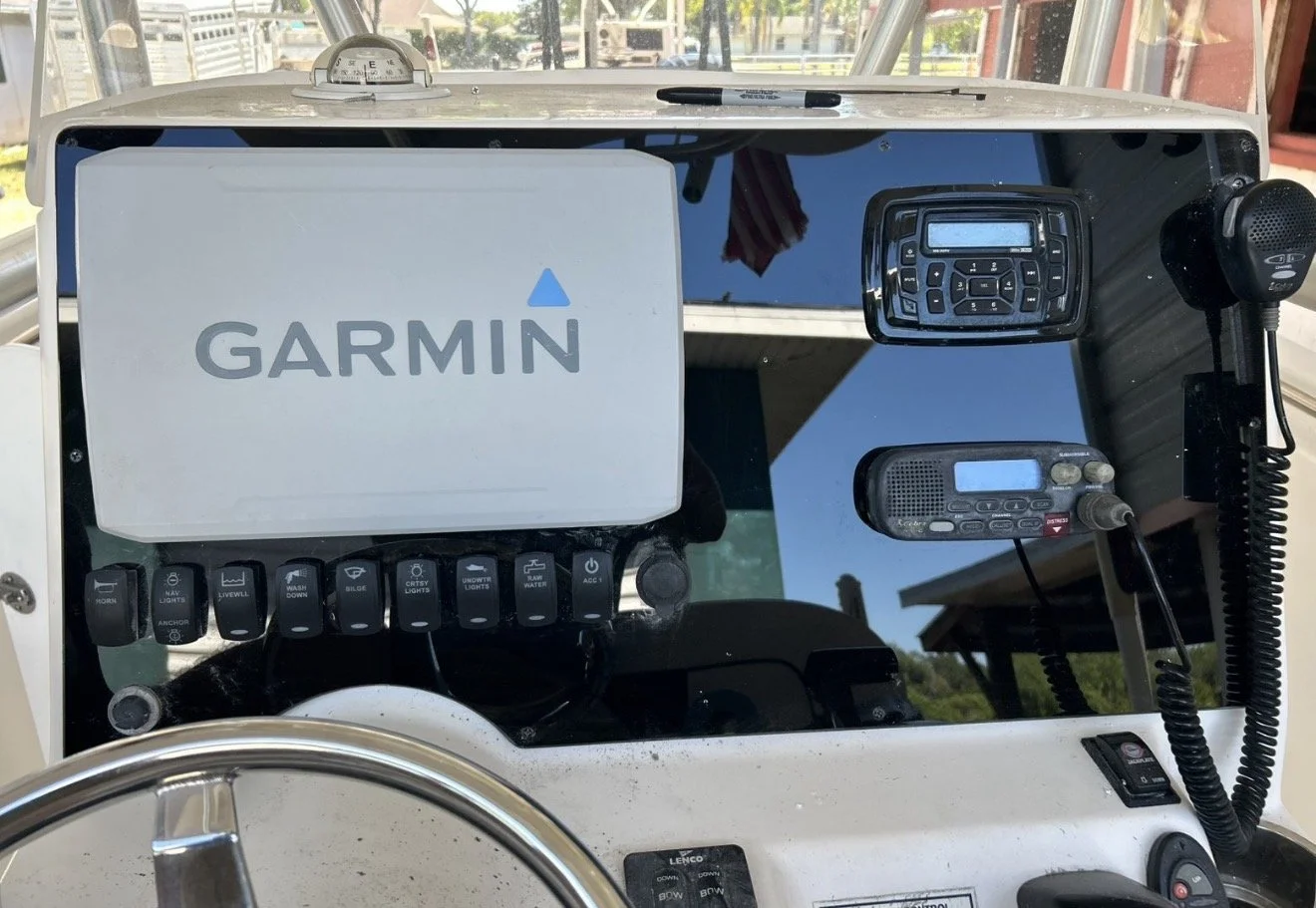 Boat dashboard with Garmin GPS, radio, controls, and communication devices.