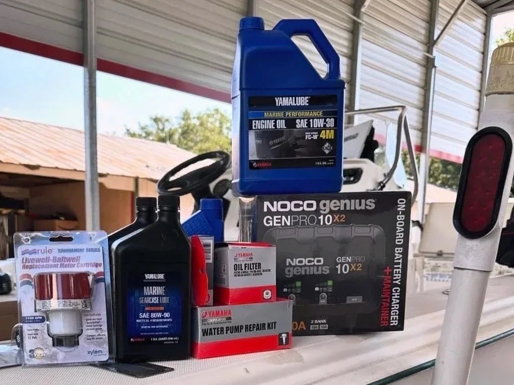 Various Yamaha motorboat maintenance supplies including engine oil, gear grease, oil filter, water pump repair kit, battery charger, and a small fuel filter.