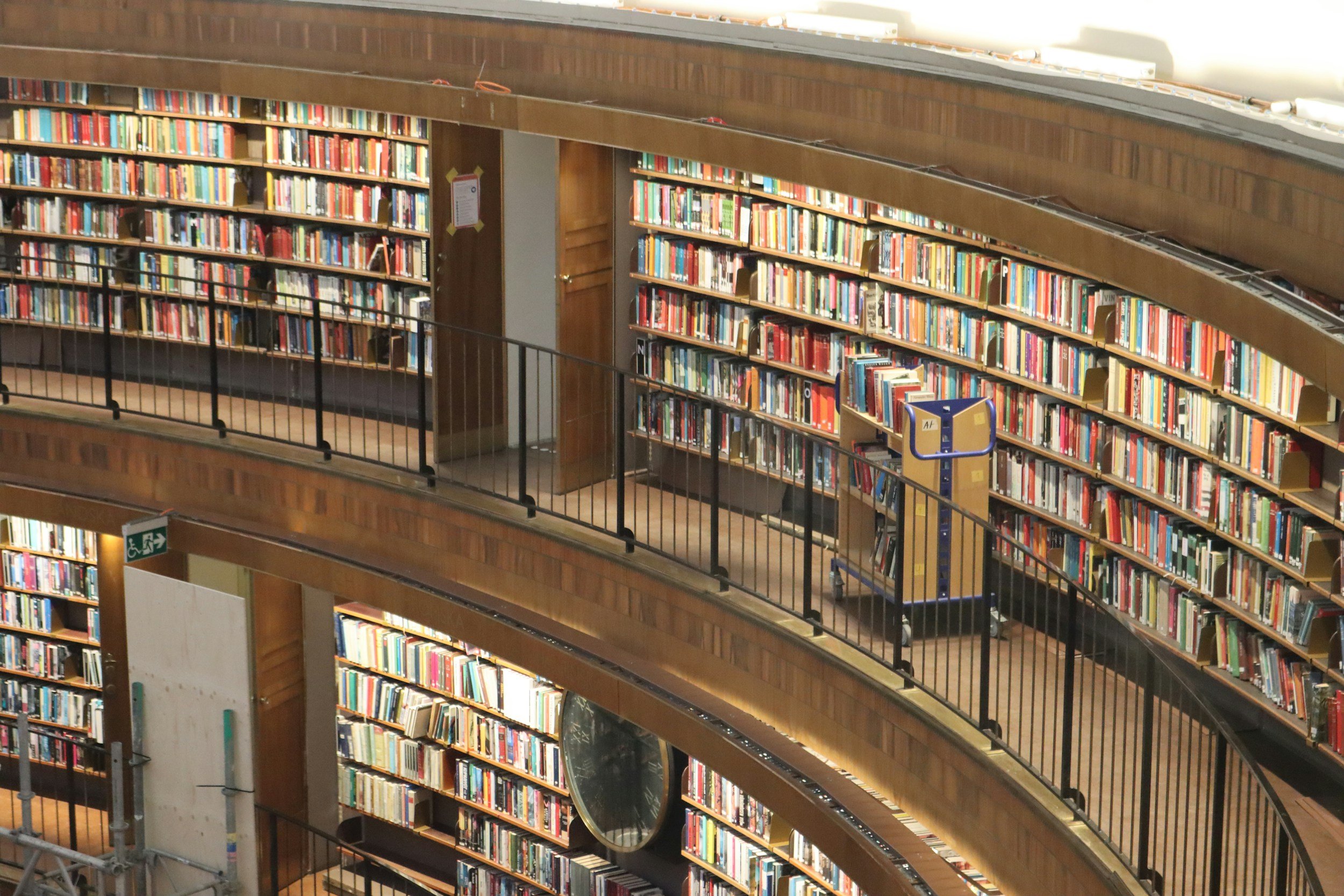 Multiple shelves filled with colorful books in a multi-level library with curved wooden balconies.
