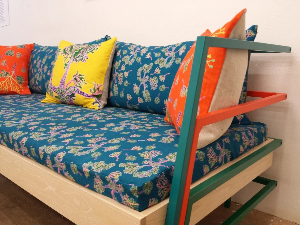 Colorful sofa with patterned cushions and a unique wooden armrest structure.