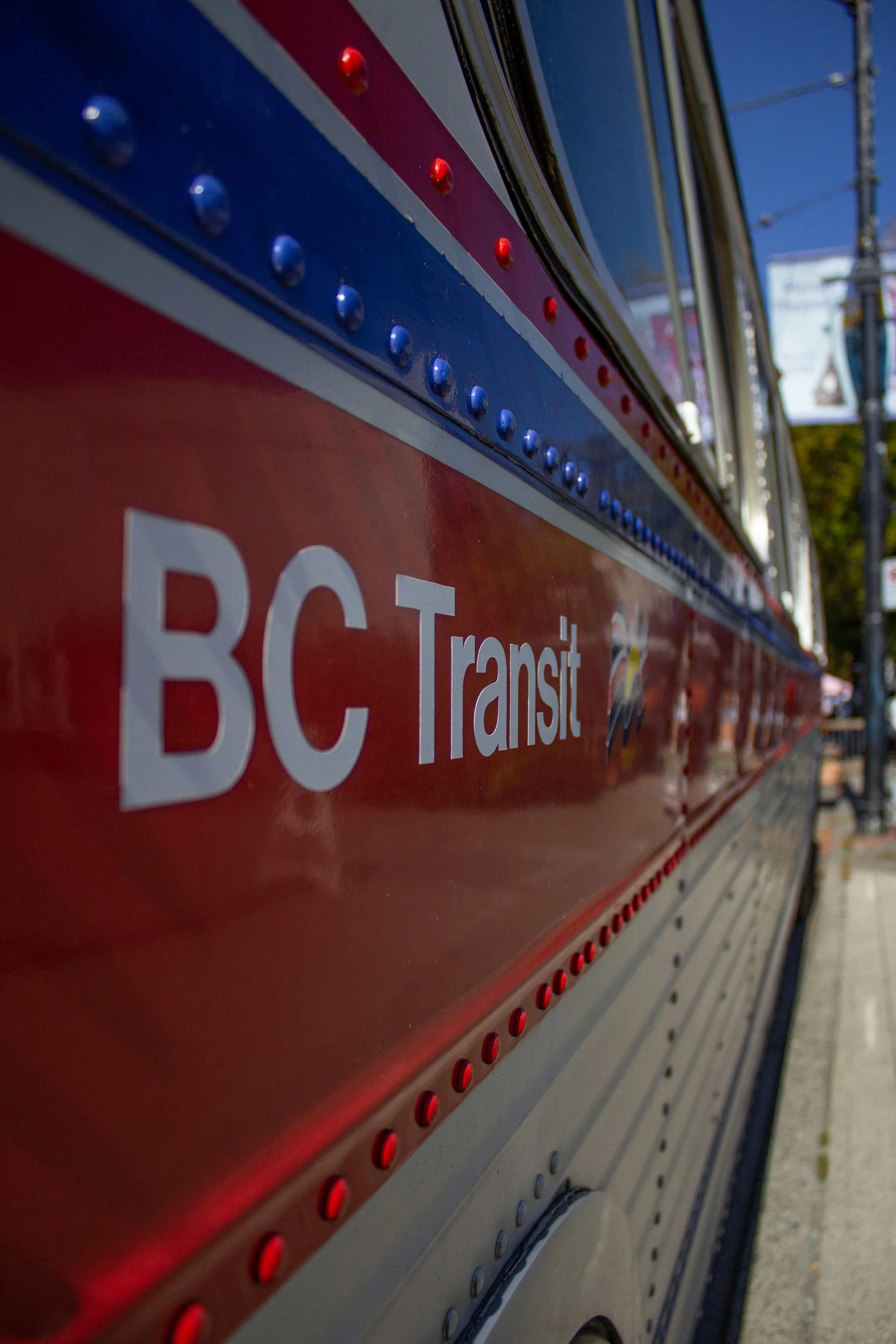 Close-up of a red and gray transit bus with blue and red lights along the side.