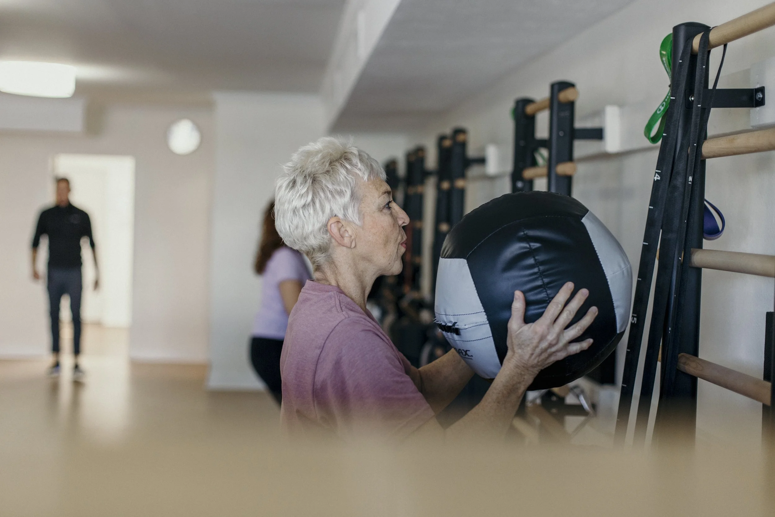 Woman over 60 holding an exercise ball during a strength training session at A50 Personal Training.
