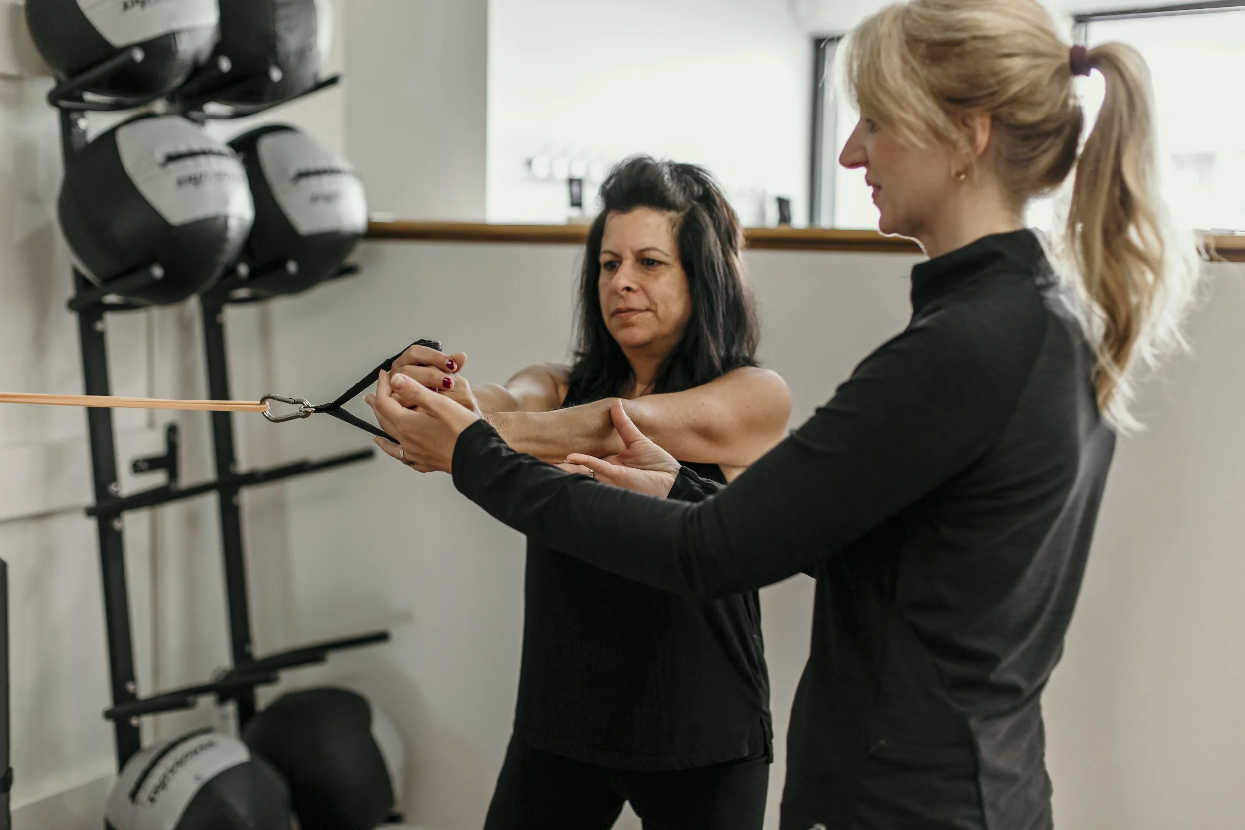 Woman performing a standing resistance band core exercise with coaching from an A50 Personal Training coach.