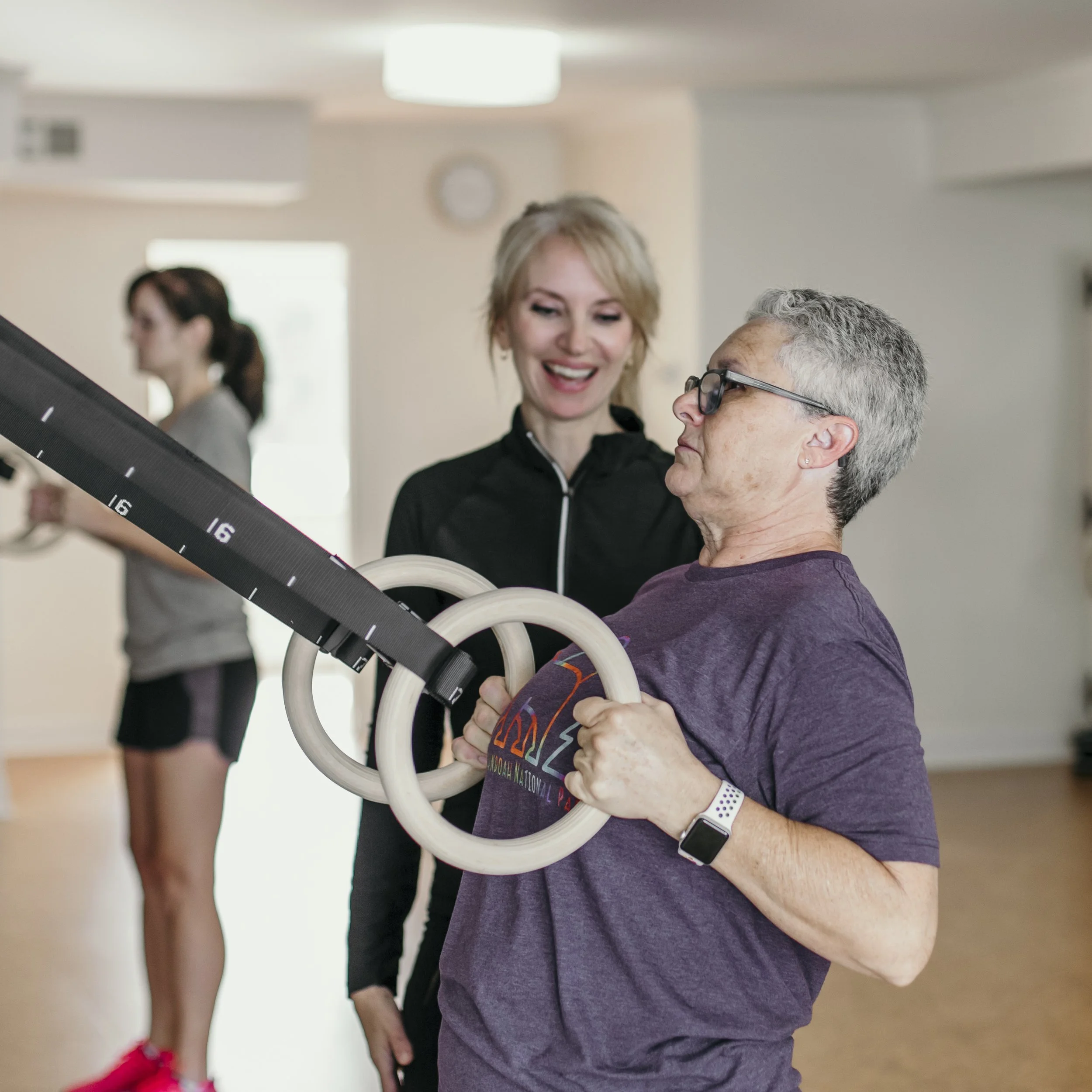 Woman over 60 performing a wooden ring row with coaching at A50 Personal Training.