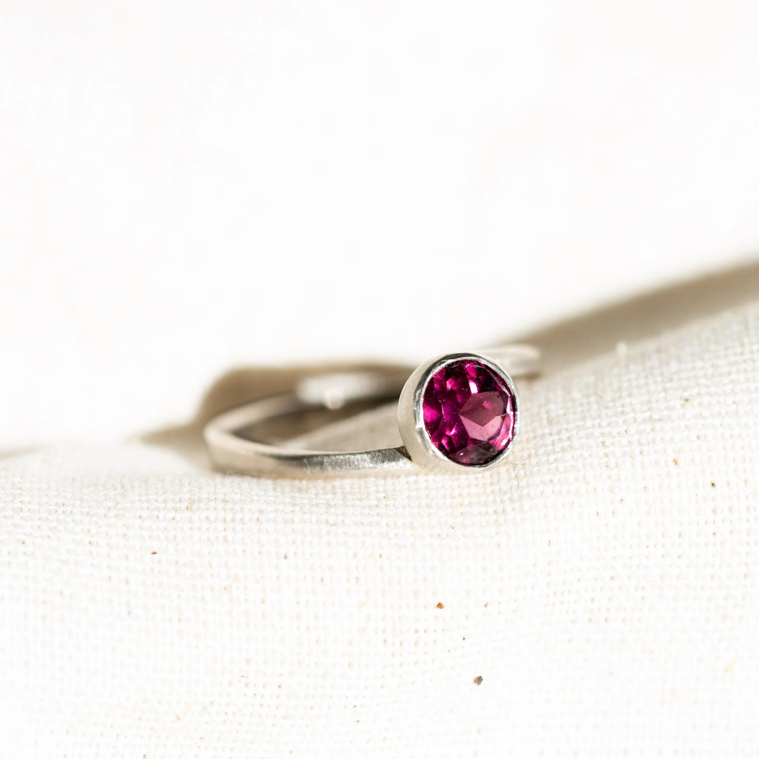 PF016

A 1.7 ct rhodolite garnet set against the cool grey of AgPd.

The tapered square band twists gently as it rises into the bezel, creating a subtle change in plane and a sense of movement around the stone. A brushed finish keeps the structure re