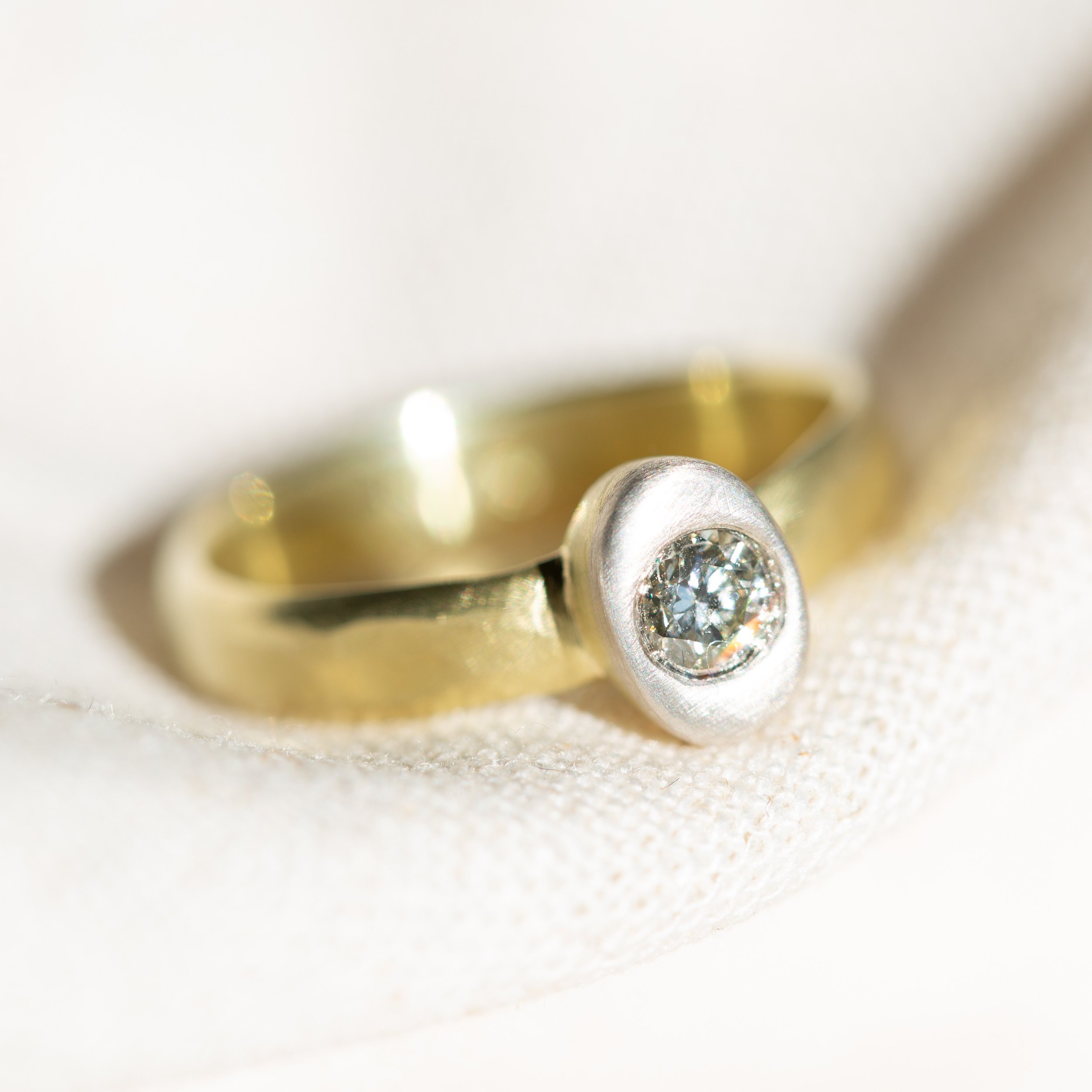 PF020

The twentieth &mdash; and final &mdash; piece of the debut collection.

18K gold forms the structure. An oval gold collet rises from the band, capped in AgPd and interrupted by a single flush-set natural diamond.

Gold beneath. Grey above. Lig