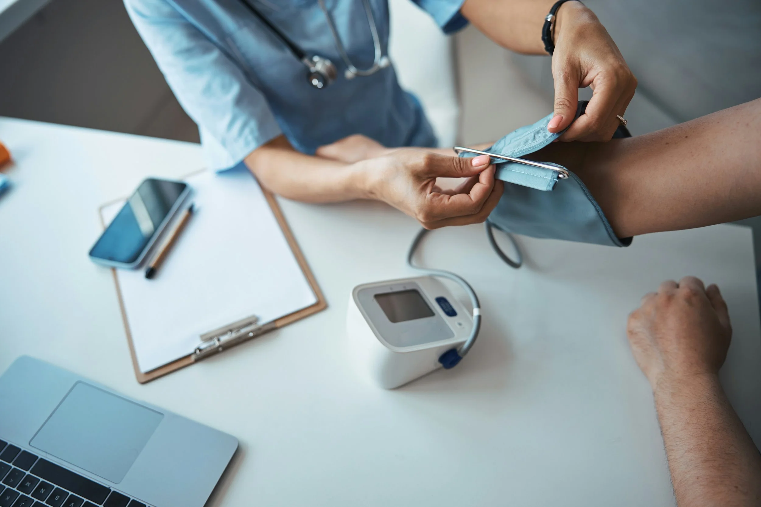 Healthcare professional taking a patient's blood pressure in a clinical setting.