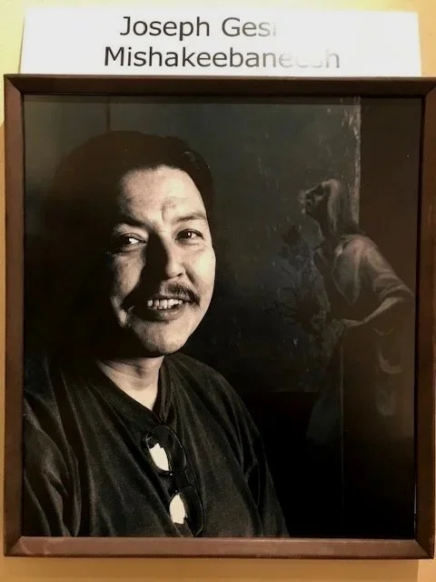 A black and white photograph of a smiling Joe Geshick, who's Ojibwe namewas  'Mishakeebaneesh'.