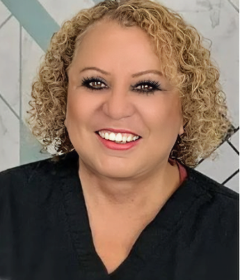 Close-up of a smiling woman with curly blonde hair, wearing a black top.