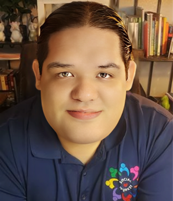 Portrait of a young person with slicked-back dark hair, wearing a navy blue polo shirt with social media logos, smiling in front of a bookshelf and decorative sculptures.