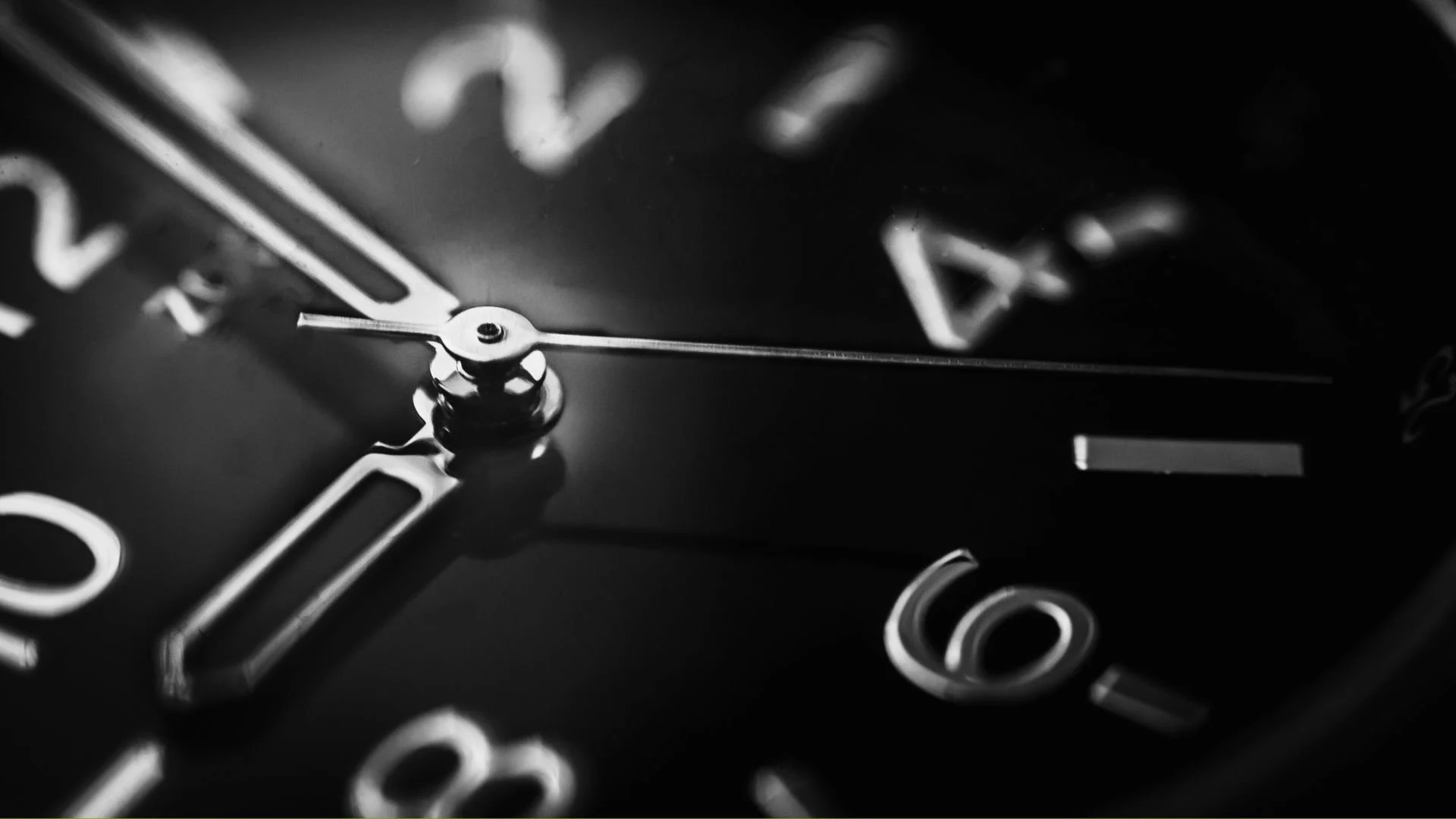 Primer plano de un reloj de agujas grandes y números en la pantalla negra.